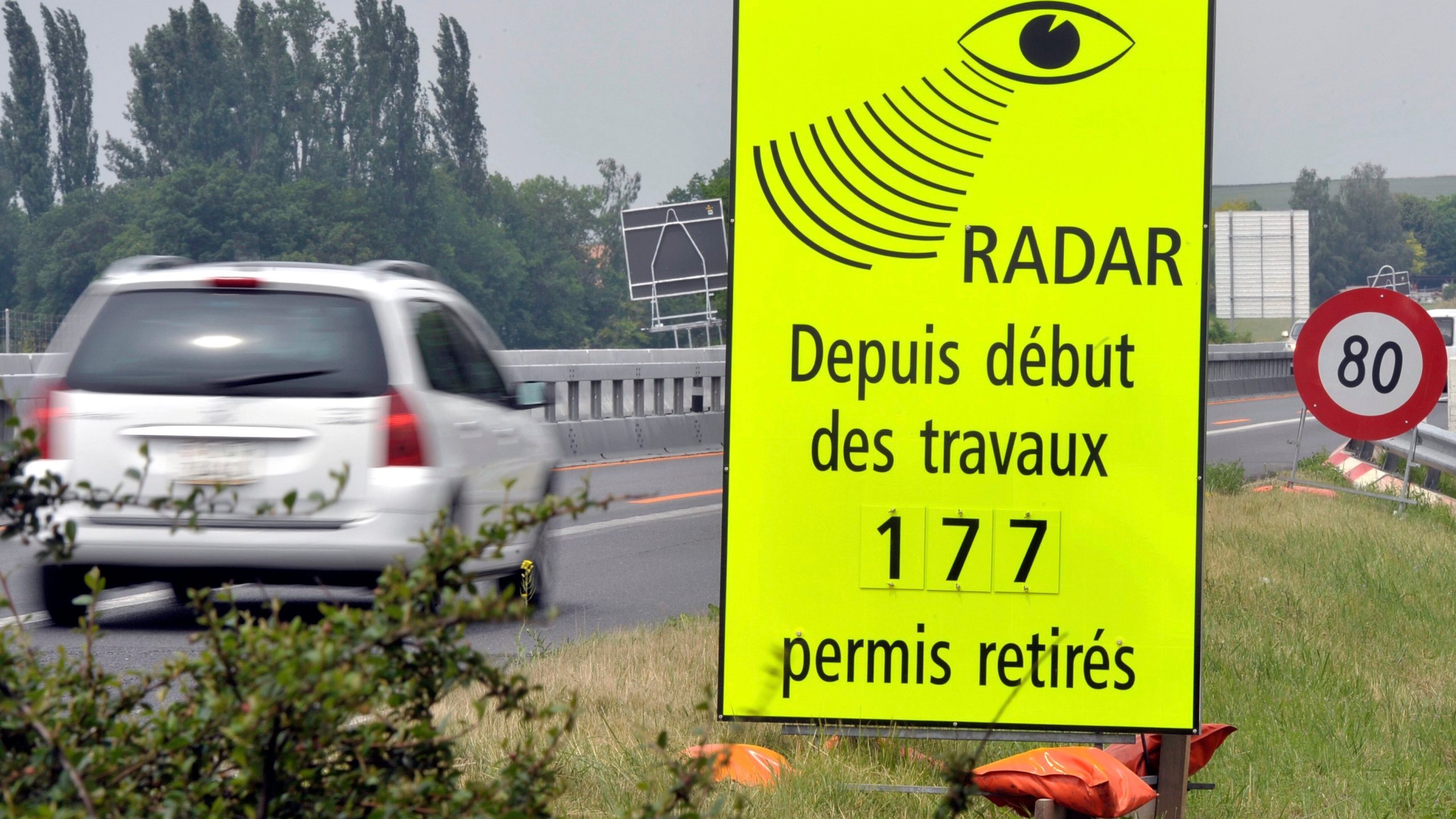 FILE - A vehicle passes in front of a sign of the Vaud Cantonal Police indicating the number of driving licences withdrawn for speeding in the construction zone on the A1 motorway between Lausanne and Yverdon, Switzerland, Tuesday, June 15, 2010. (Dominic Favre/Keystone via AP, file)