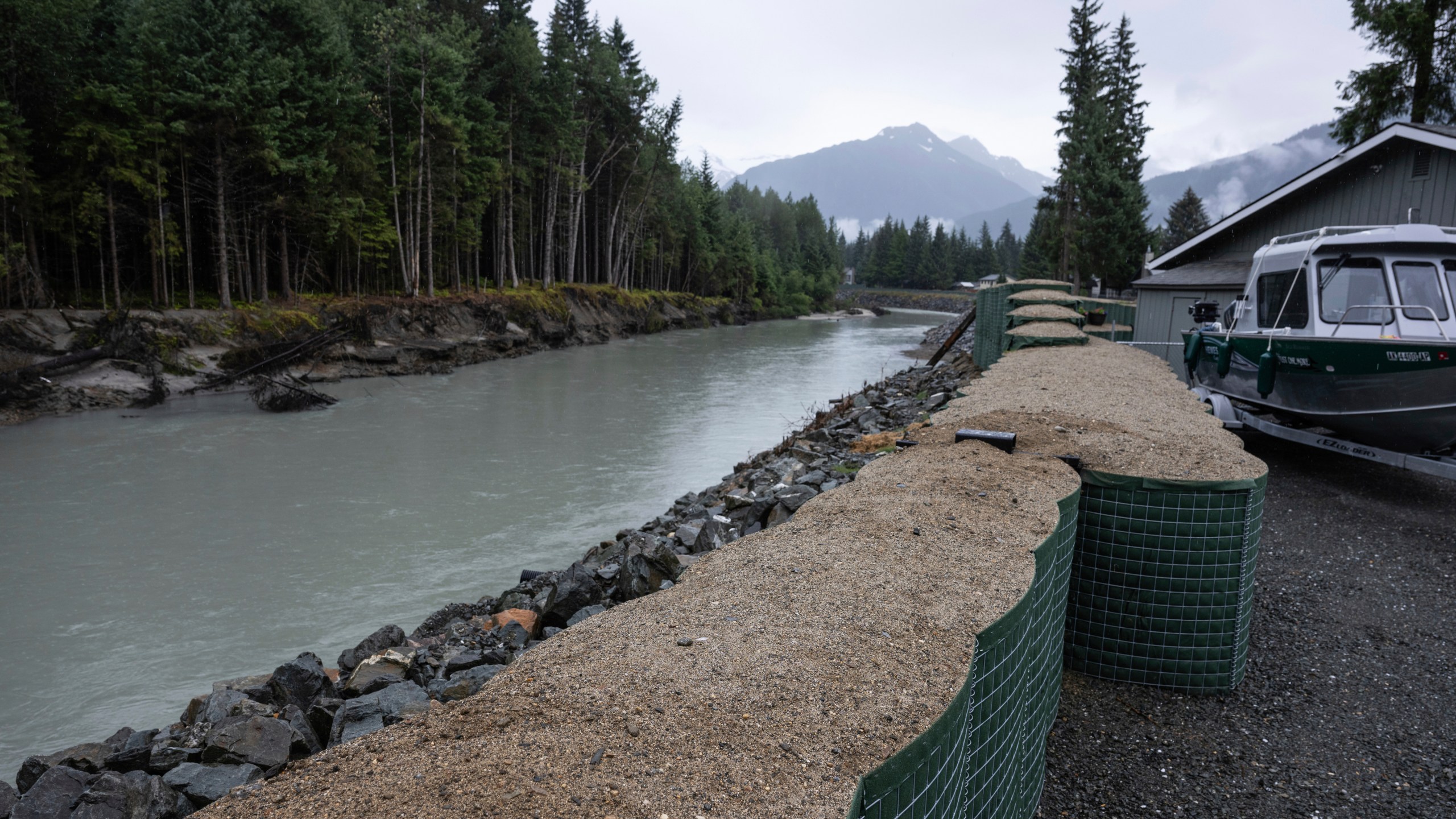 HESCO flood barriers, to protect property against glacial outburst flooding, separate a residential area from the Mendenhall River, Sunday, Aug. 3, 2025., in Juneau, Alaska. (Marc Lester/Anchorage Daily News via AP)