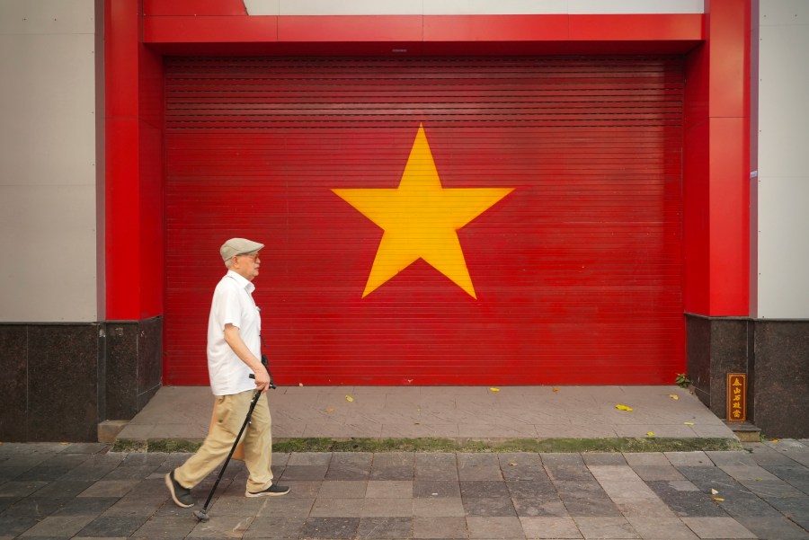 A man walks past a Vietnamese flag painted on a wall in Hanoi, Vietnam on August 12, 2025. (AP Photo/Hau Dinh)