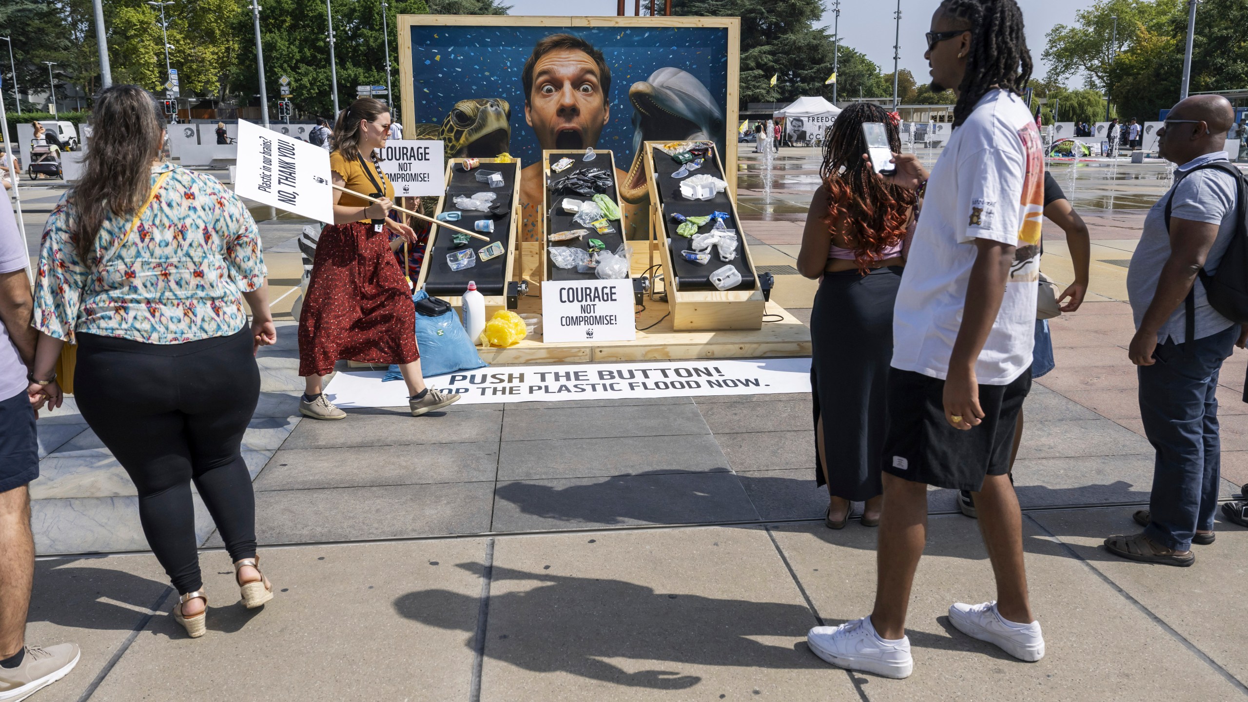 People observe a demonstration by the World Wildlife Fund against plastic waste during the ongoing plastics treaty negotiations in front of the United Nations office in Geneva, Switzerland, Wednesday, Aug. 13, 2025. (Martial Trezzini/Keystone via AP)
