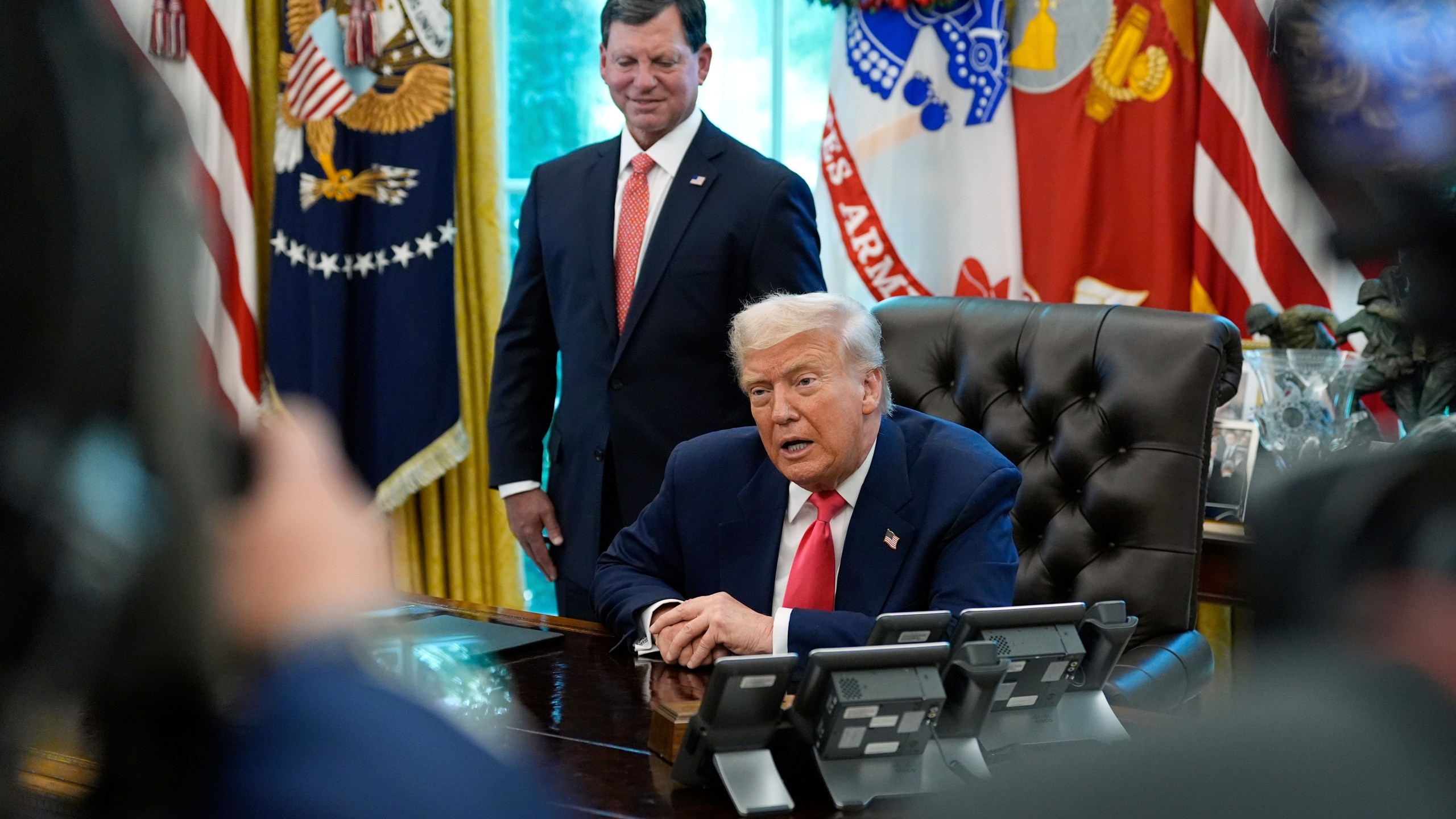 President Donald Trump speaks with reporters as Social Security Commissioner Frank Bisignano listens during an event in the Oval Office to mark the 90th anniversary of the Social Security Act, Thursday, Aug. 14, 2025, in Washington. (AP Photo/Alex Brandon)
