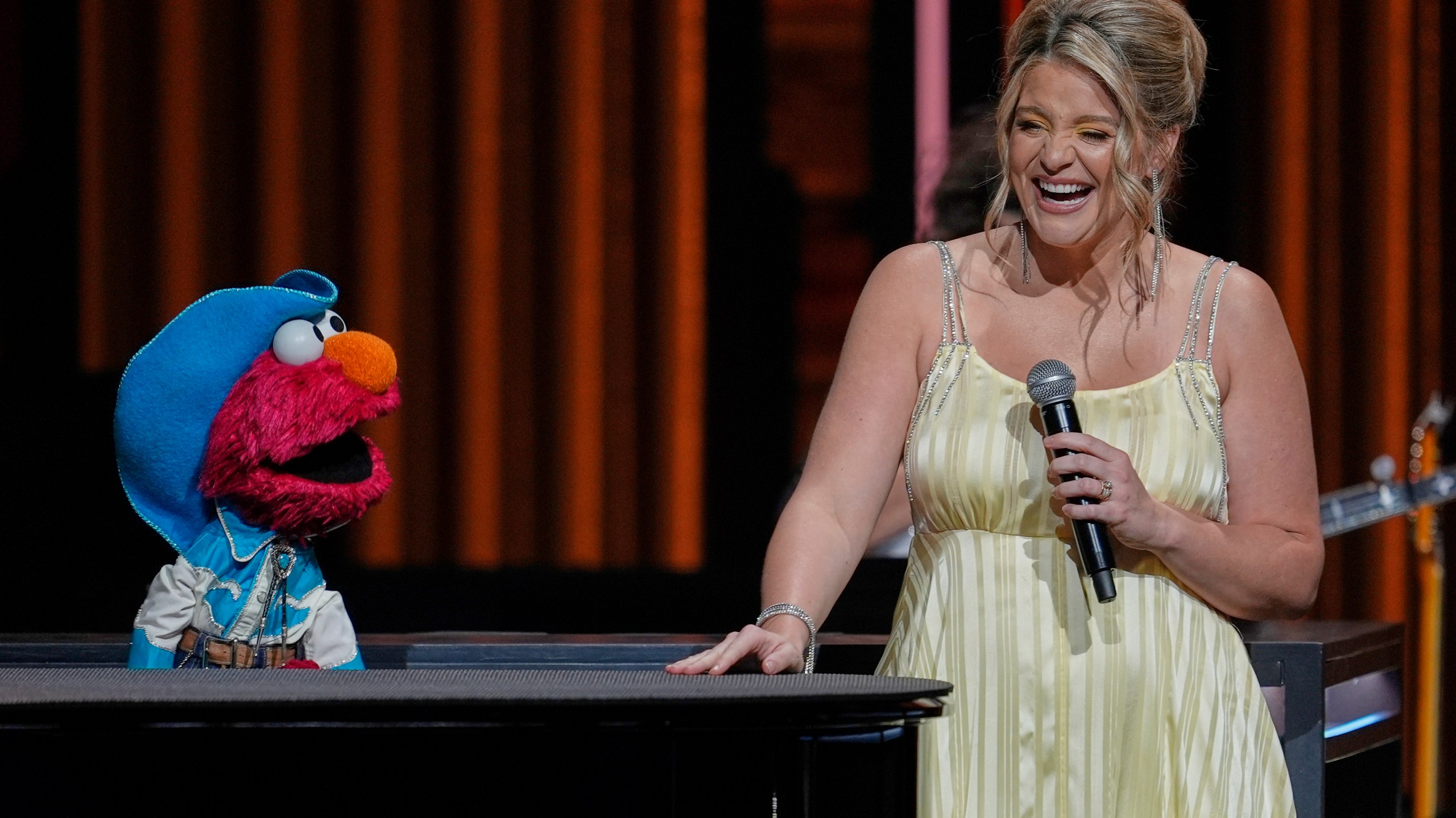 Sesame Street's Elmo, left, performs with Lauren Alaina at the Grand Ole Opry, Thursday, Aug. 14, 2025, in Nashville, Tenn. (AP Photo/George Walker IV)