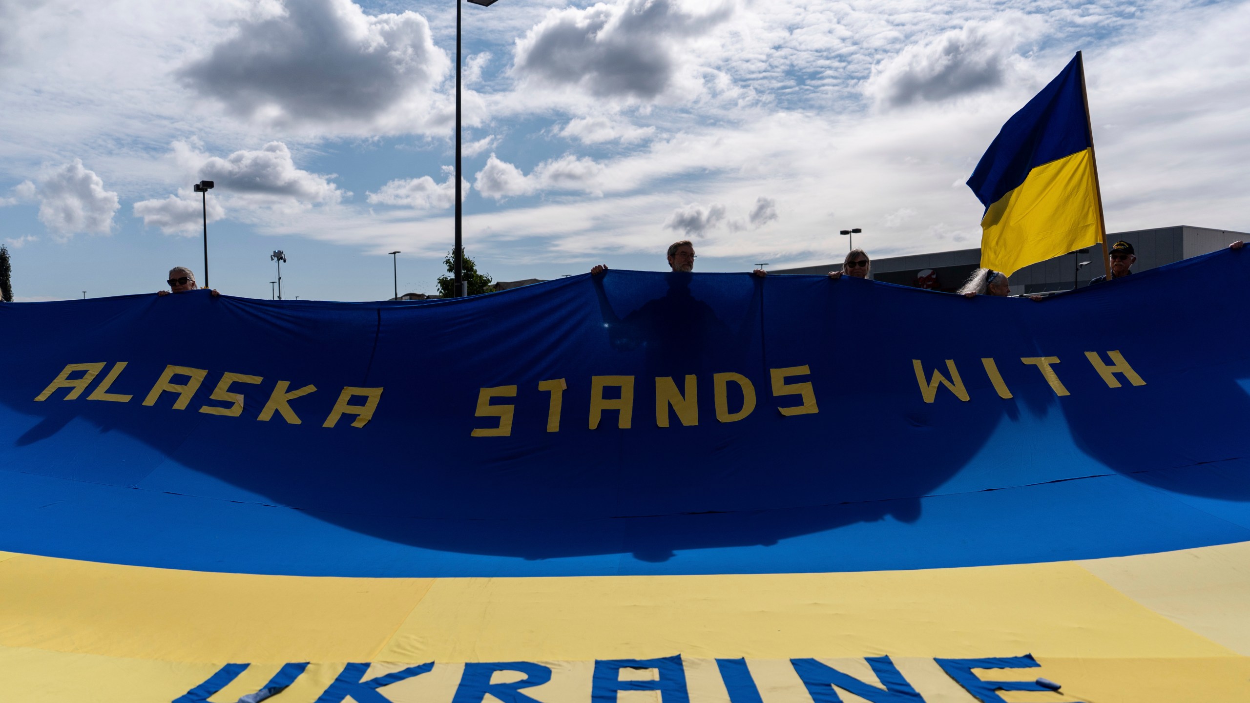 People hold a large Ukrainian flag during a rally in Anchorage, Alaska, Thursday, Aug. 14, 2025, ahead of a meeting between President Donald Trump and Russia's President Vladimir Putin. (AP Photo/Jae C. Hong)