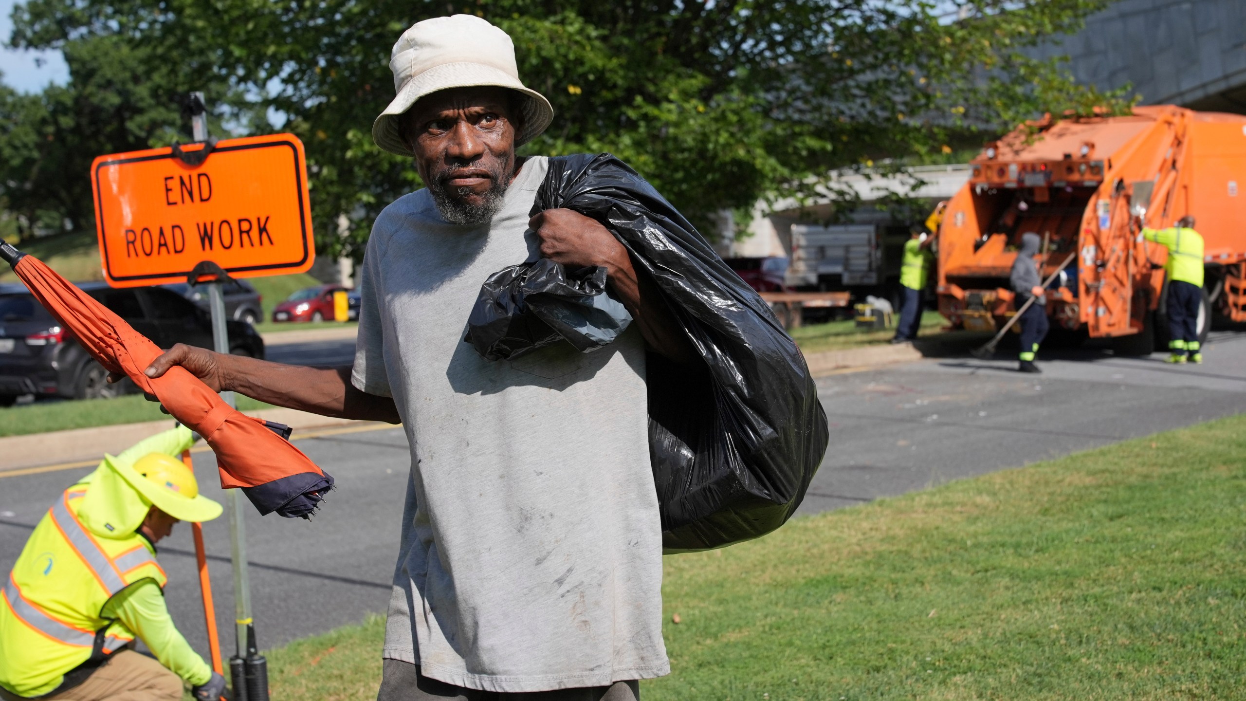 George, 67, walks away with what's left of his belongings, after the city put his mattress and other belongings in a garbage truck, Thursday, Aug. 14, 2025, in Washington. (AP Photo/Jacquelyn Martin)