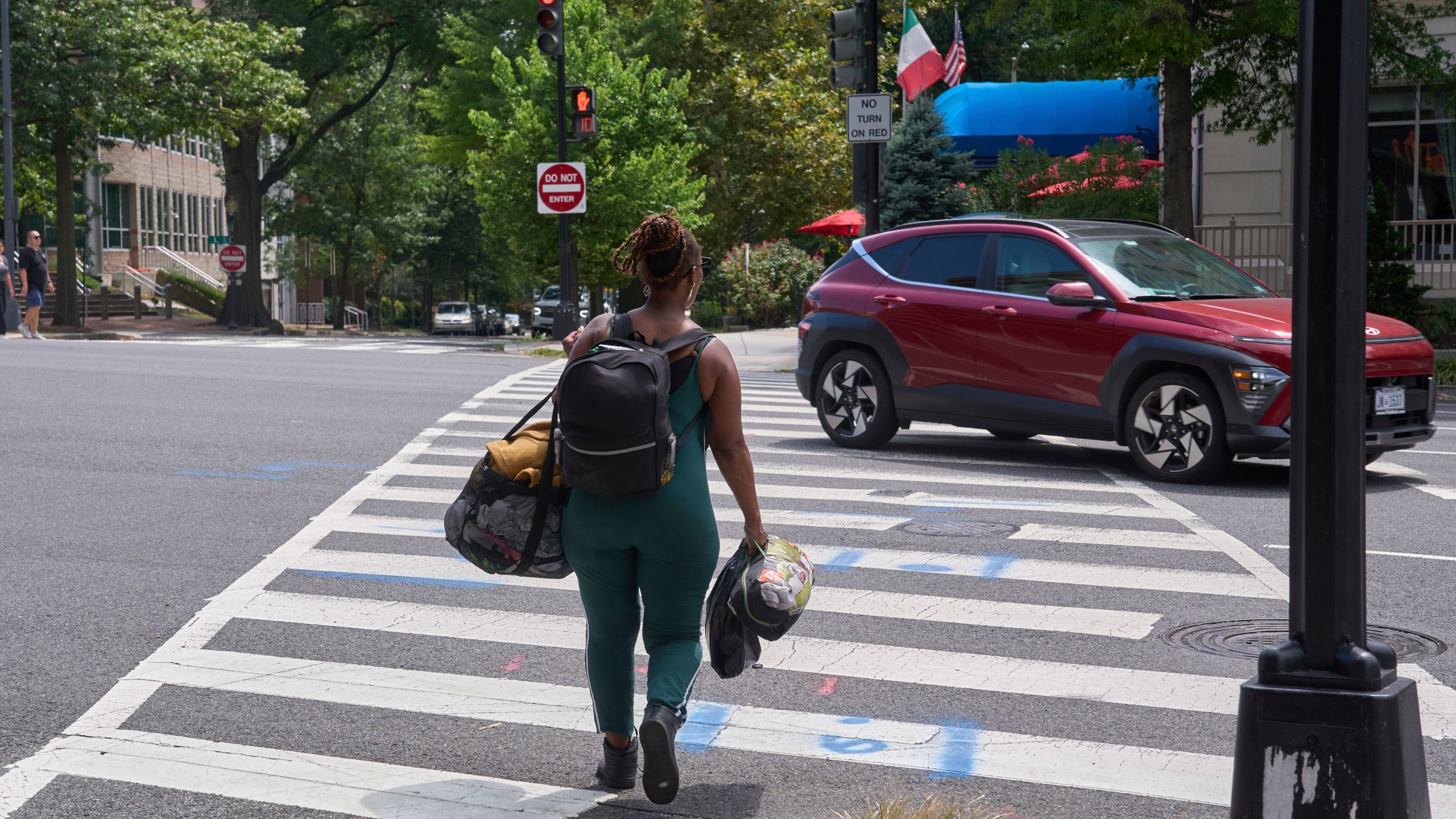 Ms. Jay, of Washington, who lost her job and is living what she calls her "Girl Scout life" while saving money by urban camping and looking for work while homeless, carries her belongings across Pennsylvania Avenue near Georgetown, Wednesday, Aug. 13, 2025, in Washington, after packing her tent after being warned by an aid organization that homeless encampments are being removed. "Last night was so scary," says Ms. Jay, "I don't want to be the one to wait until the last moment and then have to rush out." (AP Photo/Jacquelyn Martin)
