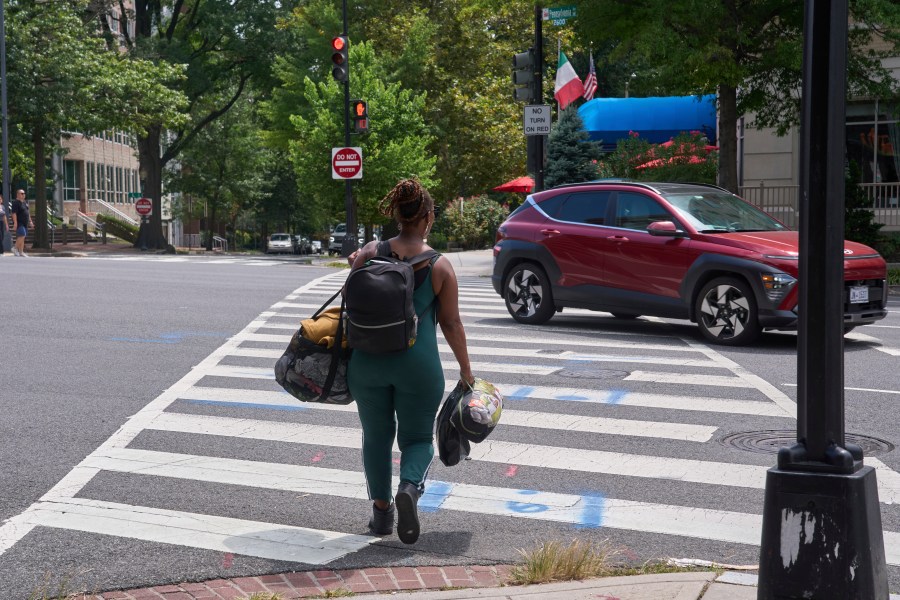 Ms. Jay, of Washington, who lost her job and is living what she calls her "Girl Scout life" while saving money by urban camping and looking for work while homeless, carries her belongings across Pennsylvania Avenue near Georgetown, Wednesday, Aug. 13, 2025, in Washington, after packing her tent after being warned by an aid organization that homeless encampments are being removed. "Last night was so scary," says Ms. Jay, "I don't want to be the one to wait until the last moment and then have to rush out." (AP Photo/Jacquelyn Martin)
