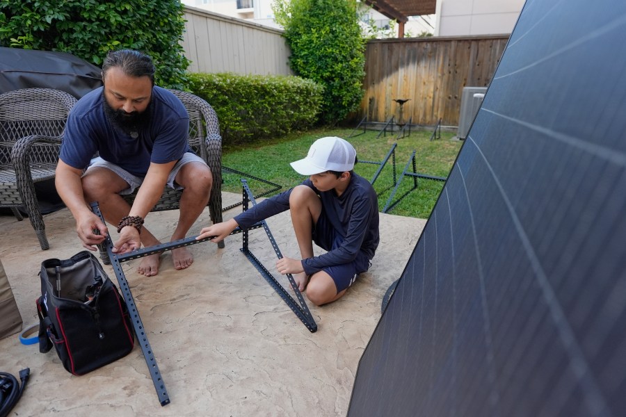 Bhavin Misra, left, and his son, Rumi, 10, assemble a Craftstrom Solar plug-in kit at their home Tuesday, Aug. 5, 2025, in Houston. (AP Photo/David J. Phillip)