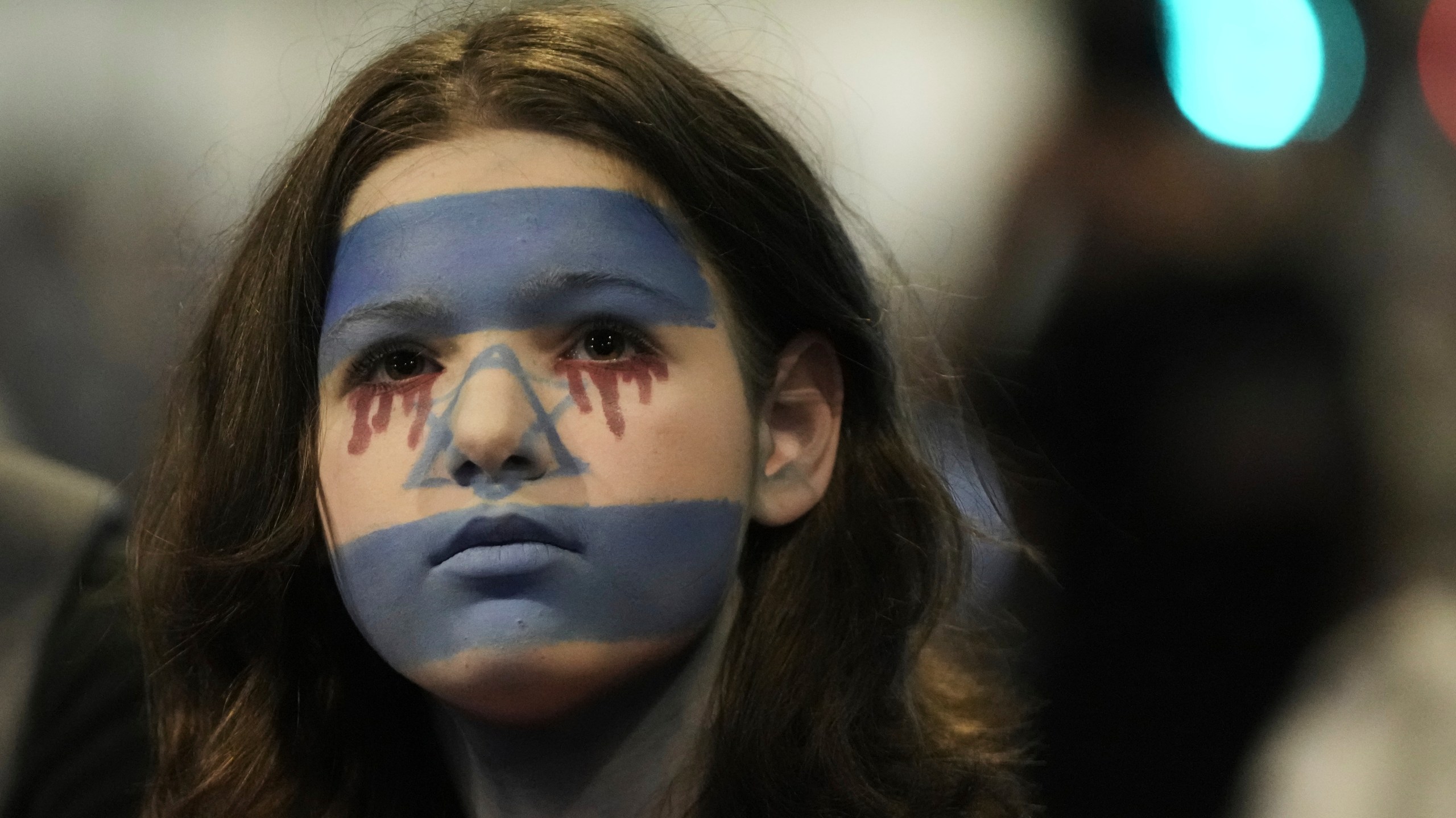A woman with her face painted in the colors of the Israeli flag takes part in a protest demanding the end of the war, the immediate release of hostages held by Hamas in the Gaza Strip, and against Prime Minister Benjamin Netanyahu's government in Tel Aviv, Saturday, Aug. 16, 2025. (AP Photo/Mahmoud Illean)