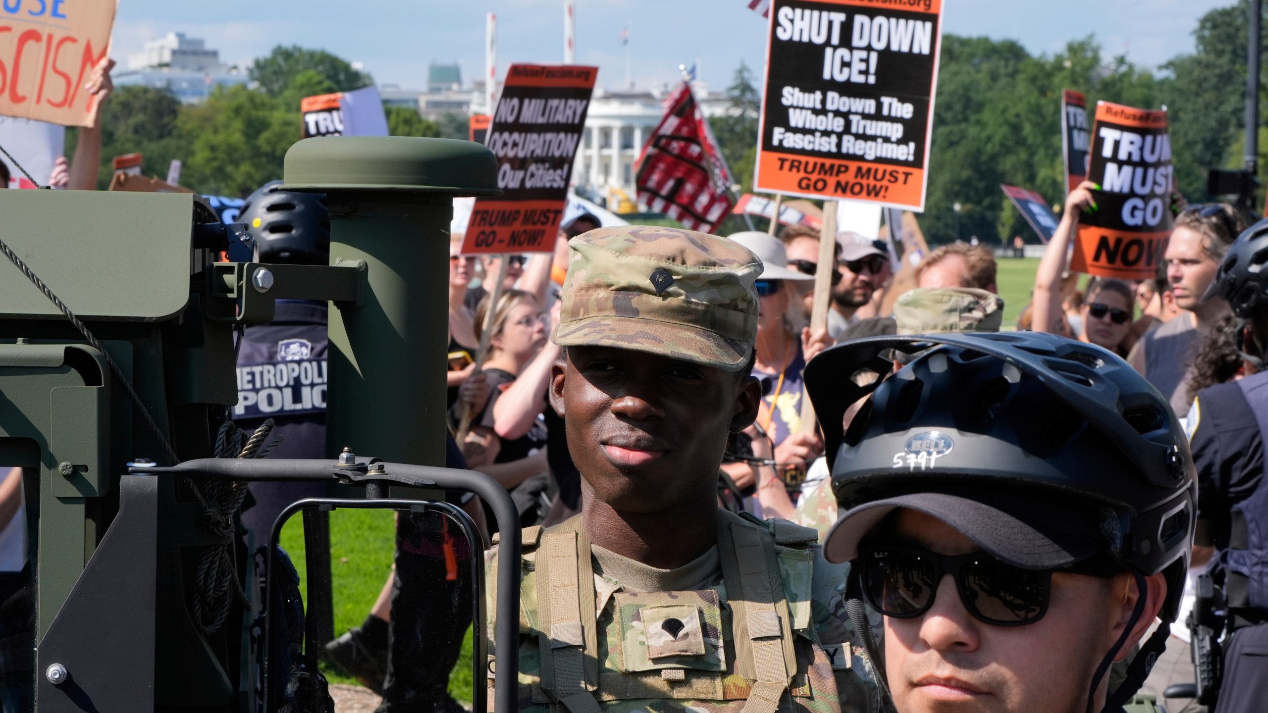 Washington Metropolitan Police officers and military police soldiers with the District of Columbia National Guard watch as activists protest President Donald Trump's federal takeover of policing of the District of Columbia, Saturday, Aug. 16, 2025, in Washington. (AP Photo/Alex Brandon)
