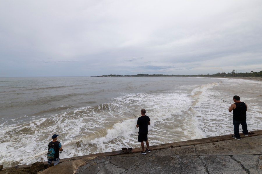 People fish along the shore in Arecibo, Puerto Rico, as Hurricane Erin brings rains to the island, Sunday, Aug. 17, 2025. (AP Photo/Alejandro Granadillo)