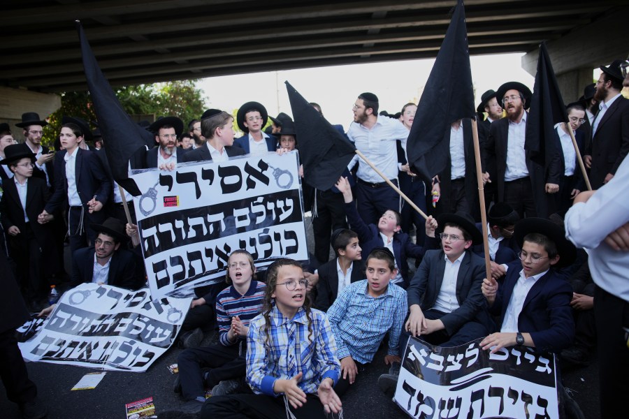 Ultra-Orthodox Jews block a highway during a protest against army recruitment, in Bnei Brak, Israel, Tuesday, Aug. 19, 2025. (AP Photo/Ohad Zwigenberg)