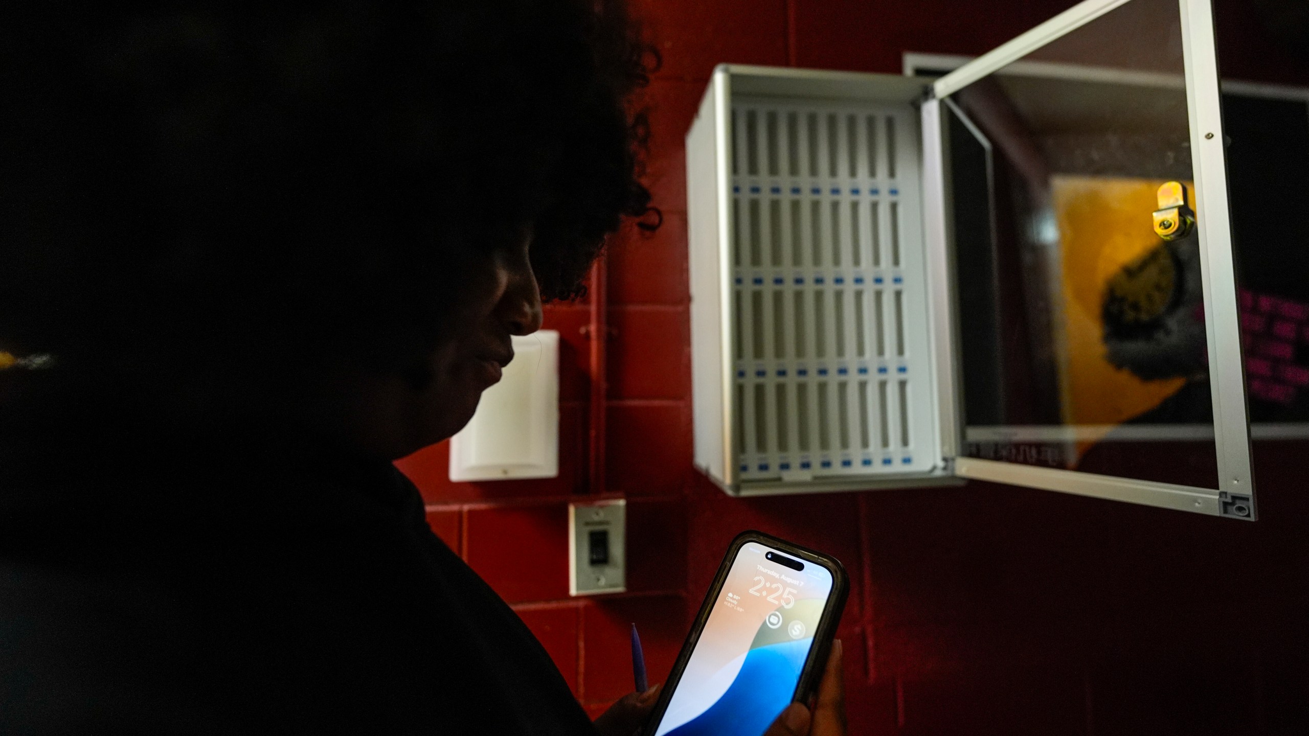 Student Audreanna Johnson views her cell phone near a cell phone locker at Ronald McNair Sr. High School, Thursday, Aug. 7, 2025, in Atlanta. (AP Photo/Mike Stewart)