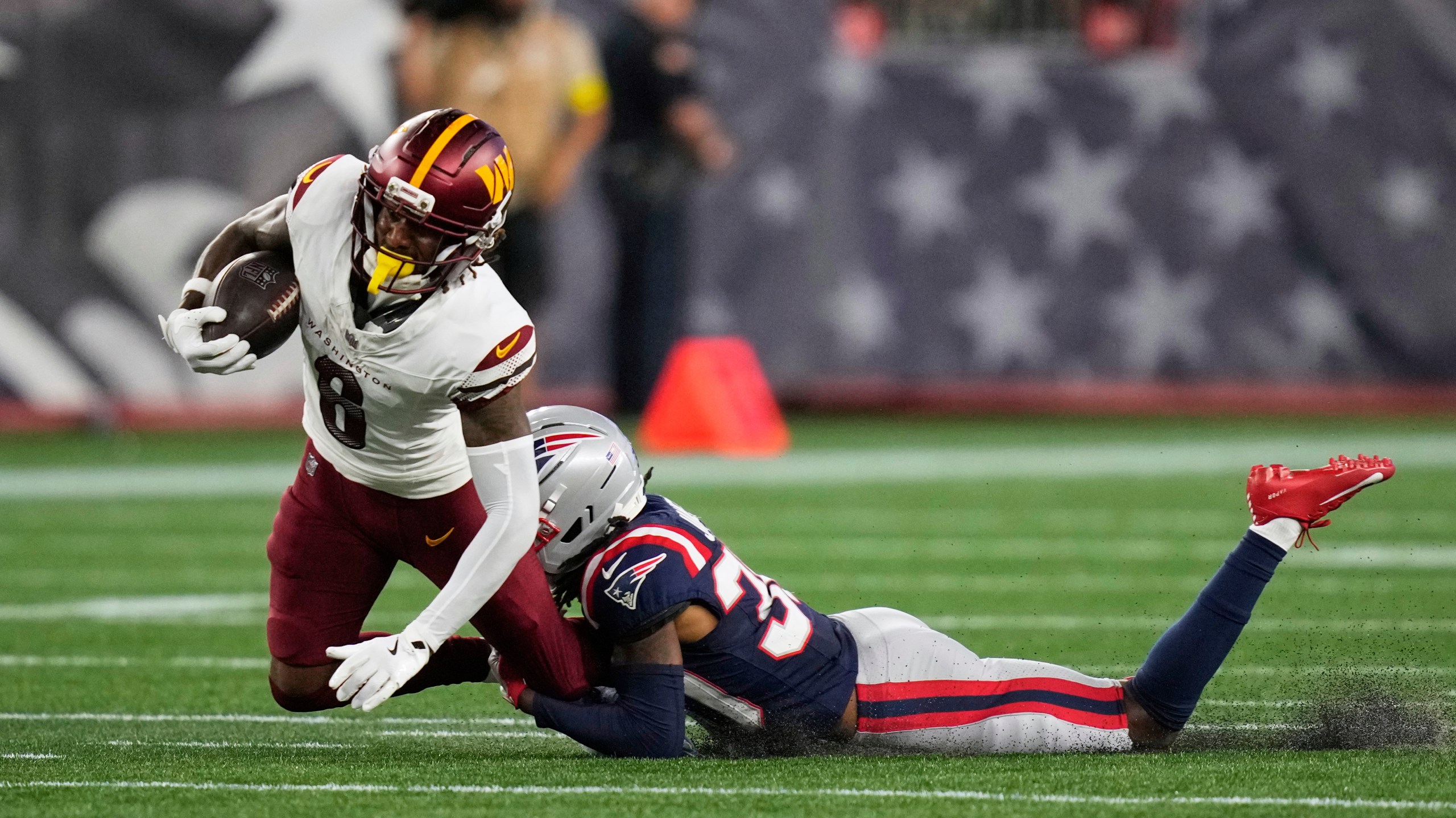 New England Patriots cornerback DJ James, right, tackles Washington Commanders running back Brian Robinson Jr. (8) during the first half of an NFL preseason football game Friday, Aug. 8, 2025, in Foxborough, Mass. (AP Photo/Charles Krupa)