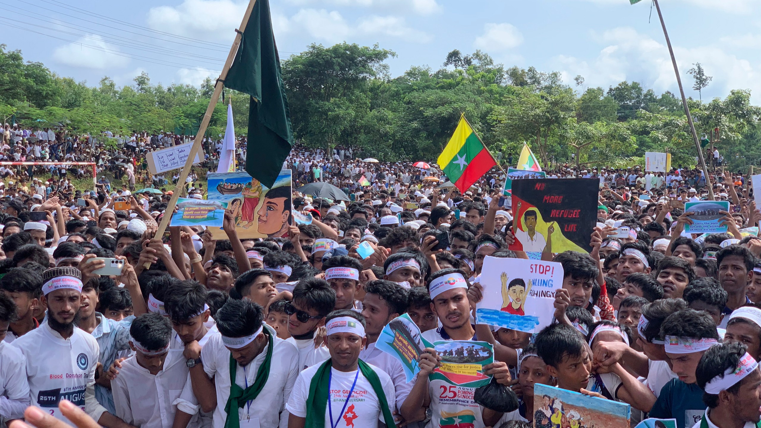 Rohingya refugees gather as they hold placards and flags to demand safe return to Myanmar's Rakhine state as they mark the eighth anniversary of their mass exodus at their refugee camp at Kutupalong in Cox's Bazar district, Bangladesh, Monday, Aug. 25, 2025. (AP Photo/Shafiqur Rahman)