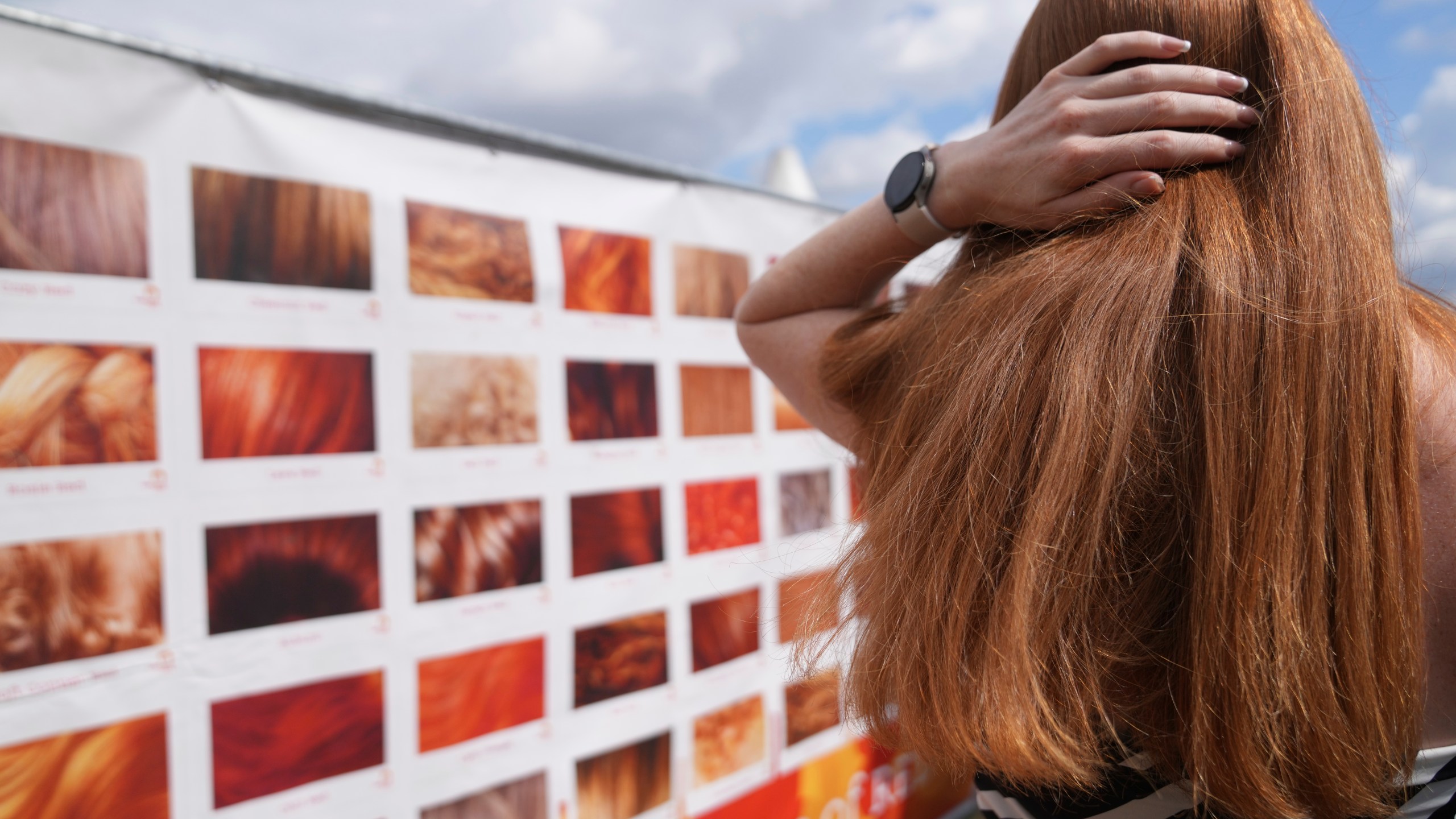 A participant checks her hair color on a chart of gradations of red during the Red Head Days festival in Tilburg, Netherlands, Saturday, Aug. 30, 2025. (AP Photo/Virginia Mayo)