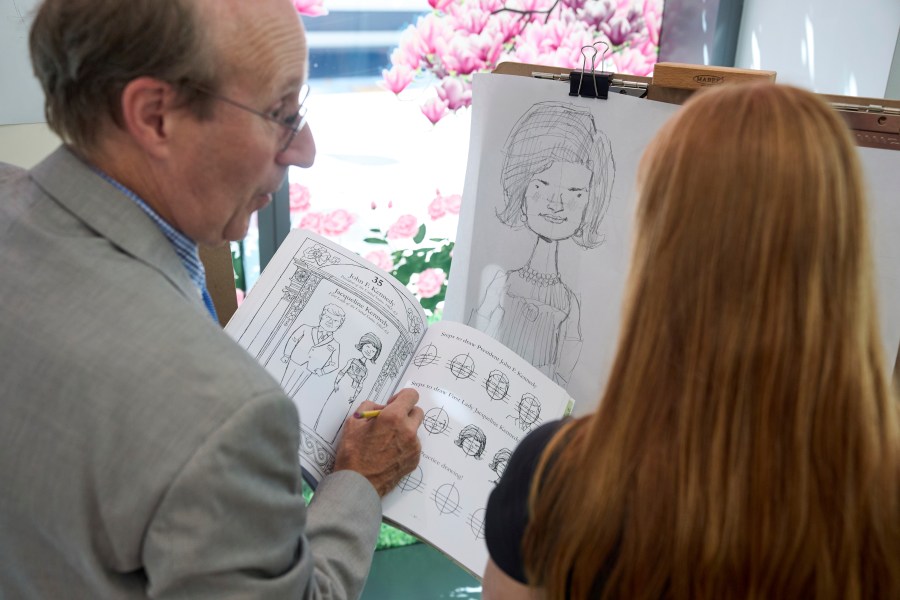 John Hutton, illustrator and professor of art history at Salem College, shows Adelaide Baldus, 16, of La Plata, Md., how to draw a picture of first lady Jacqueline Kennedy, Tuesday, Aug. 12, 2025, from his book, "How To Draw The Presidents and First Ladies," at The People's House, a museum in Washington. (AP Photo/Jacquelyn Martin)