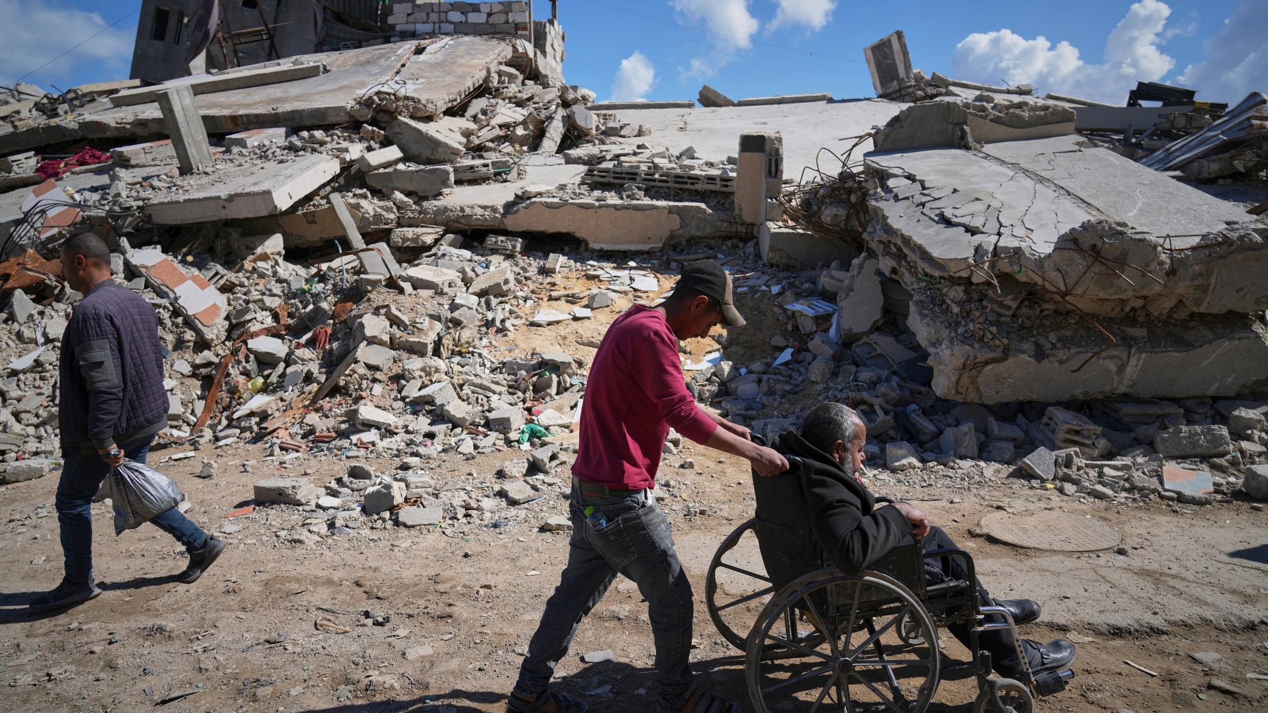 FILE - Wasem Attiya pushes his father, Mohamed, 54, in a wheelchair as they head to Shifa hospital in Gaza City for a dialysis session, Monday, April 14, 2025. (AP Photo/Jehad Alshrafi, File)