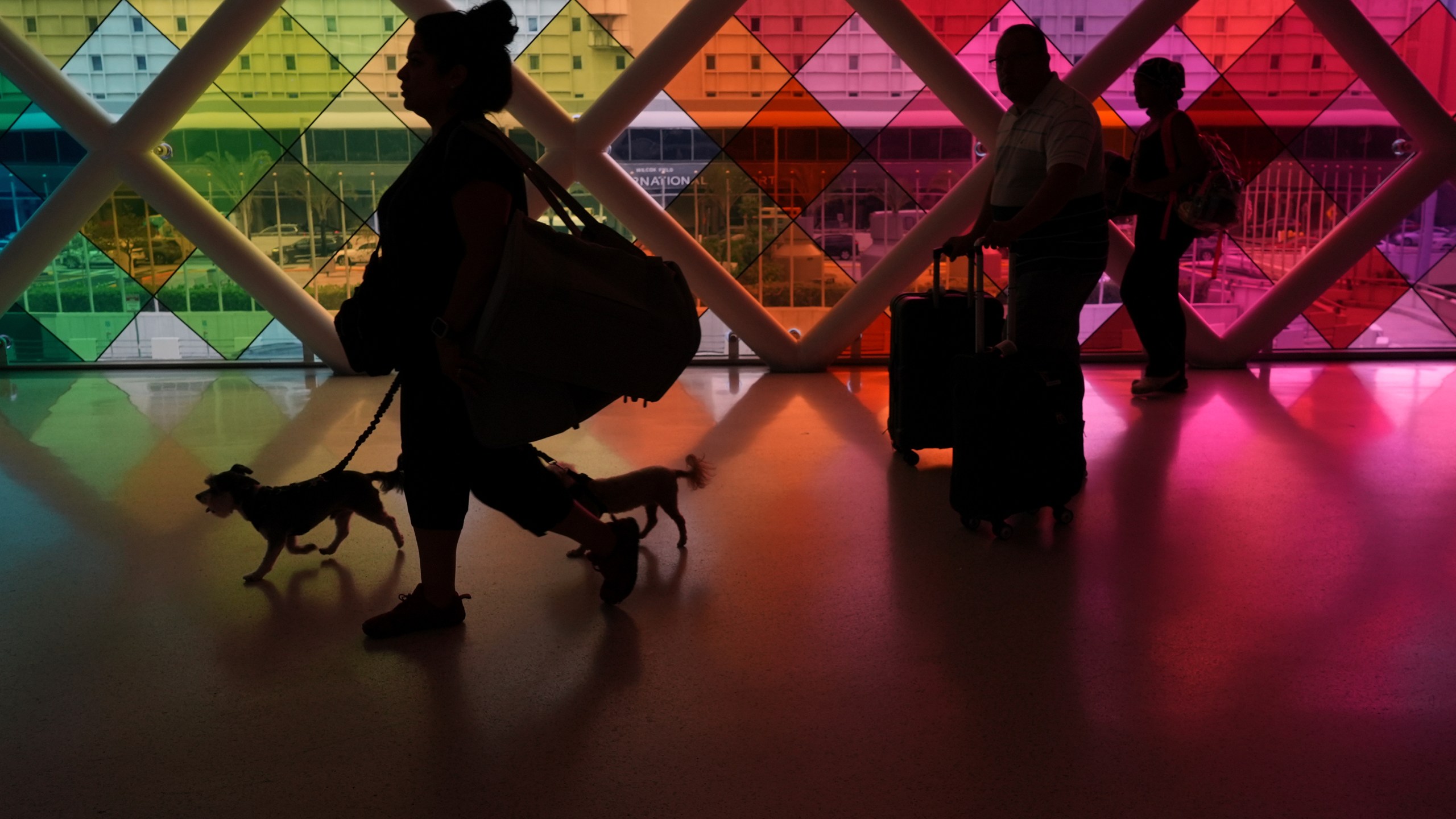 Travelers walk toward an exit at Miami International Airport at the start of the Labor Day weekend, Friday, Aug. 29, 2025, in Miami. (AP Photo/Rebecca Blackwell)