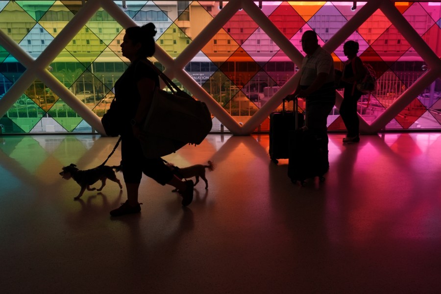 Travelers walk toward an exit at Miami International Airport at the start of the Labor Day weekend, Friday, Aug. 29, 2025, in Miami. (AP Photo/Rebecca Blackwell)