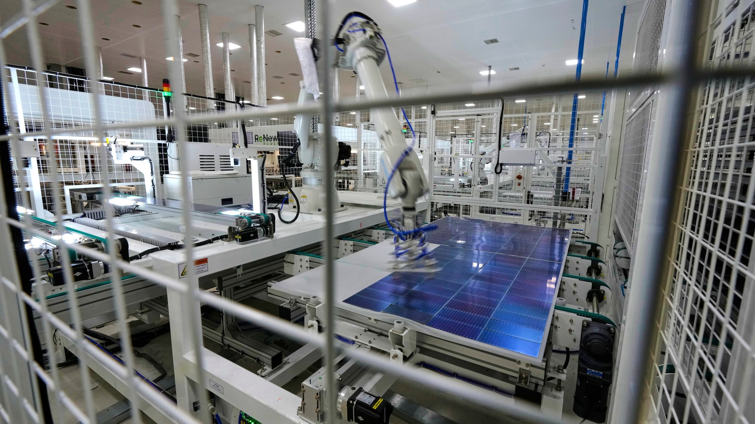 A robot places solar cells on a glass panel at a ReNew manufacturing plant on the outskirts of Jaipur, India, Thursday, Aug. 21, 2025. (AP Photo/Manish Swarup)