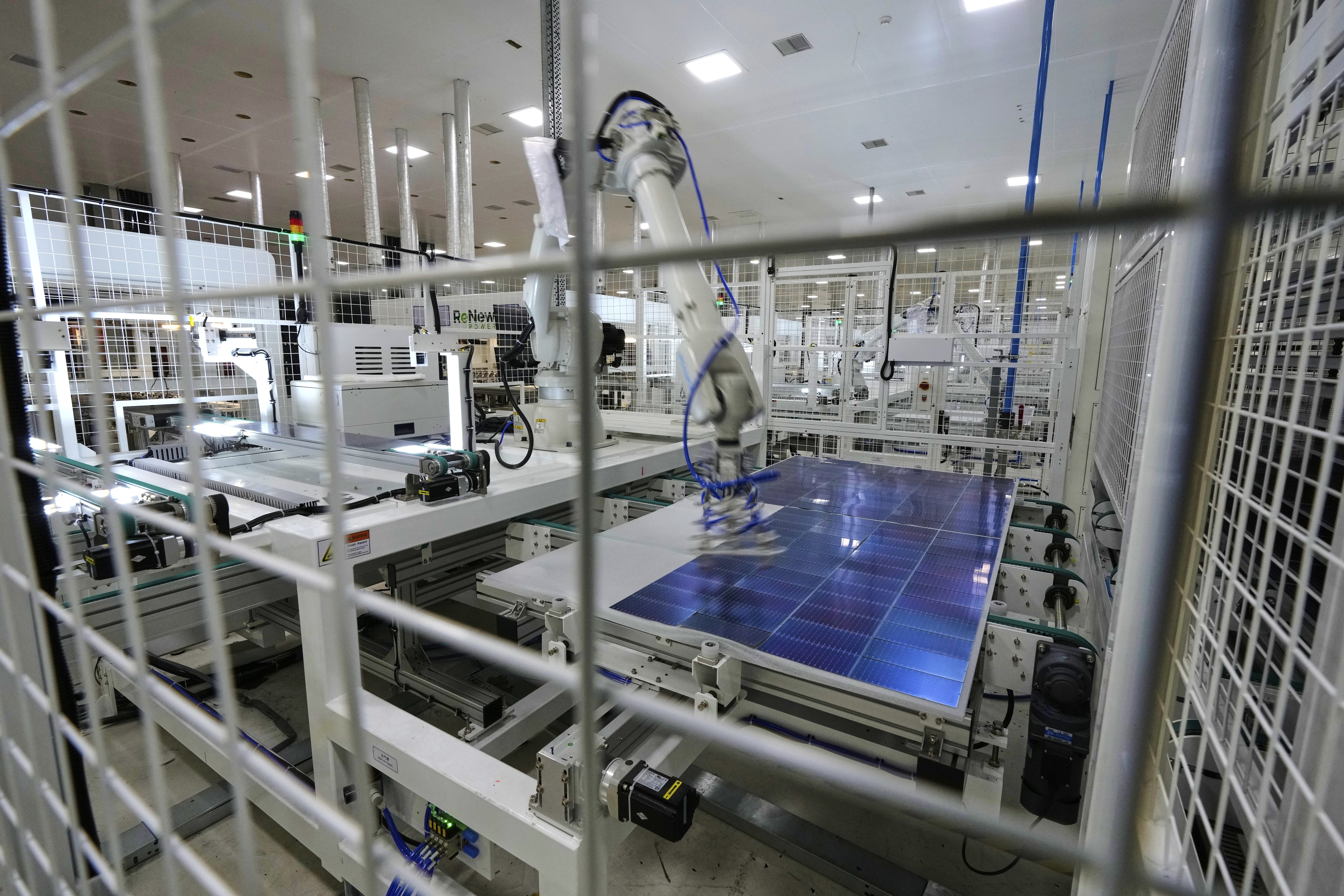 A robot places solar cells on a glass panel at a ReNew manufacturing plant on the outskirts of Jaipur, India, Thursday, Aug. 21, 2025. (AP Photo/Manish Swarup)