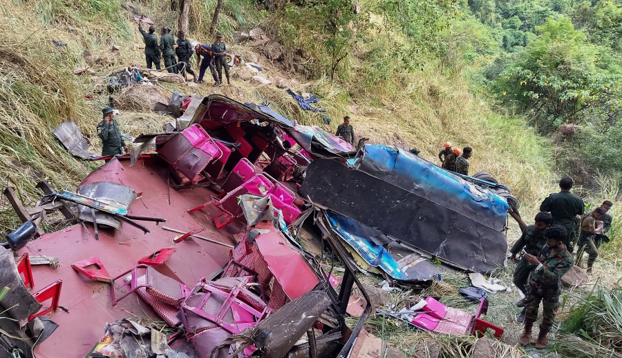 Soldiers and rescue workers stand by the debris of a passenger bus after it plunged into a precipice in Wellawaya, Sri Lanka, Friday, Sept. 5, 2025. (AP Photo/Prasanna Pathmasiri)
