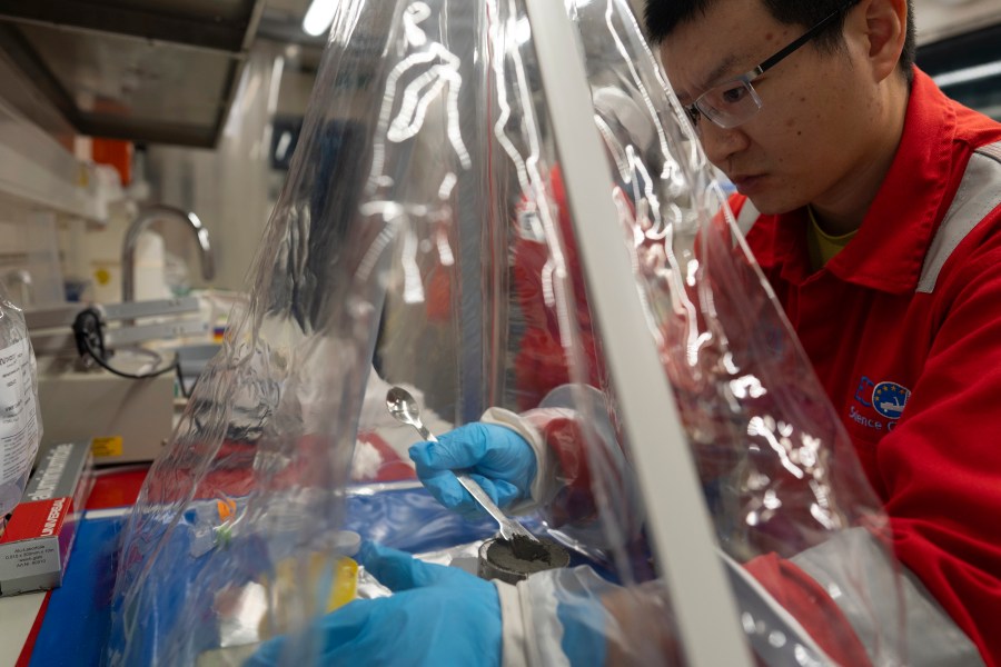 Expedition 501 researchers Xinxu Zhang, of Shenzhen University China, works in a container to ensure a sterile environment aboard the Liftboat Robert platform, in the North Atlantic, Sunday, July 20, 2025. (AP Photo/Carolyn Kaster)