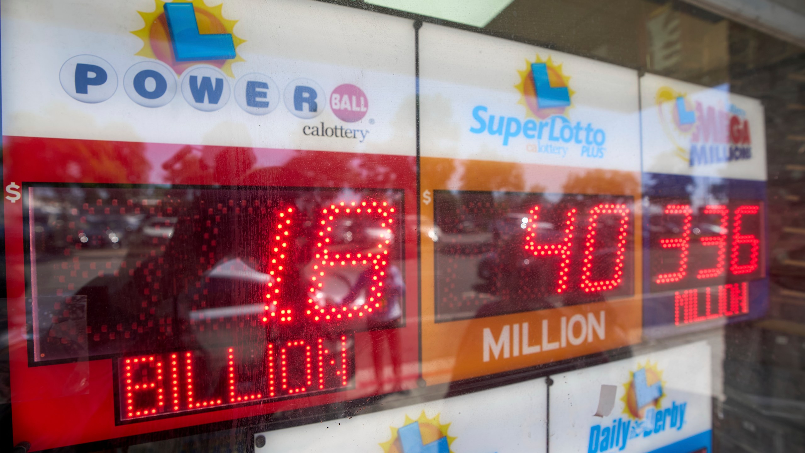An electronic sign reads $1.8 billion as crowds wait in line to buy lottery tickets at the Bluebird Liquor store in Hawthorne, Calif., on Friday, Sept. 5, 2025. (AP Photo/Damian Dovarganes)