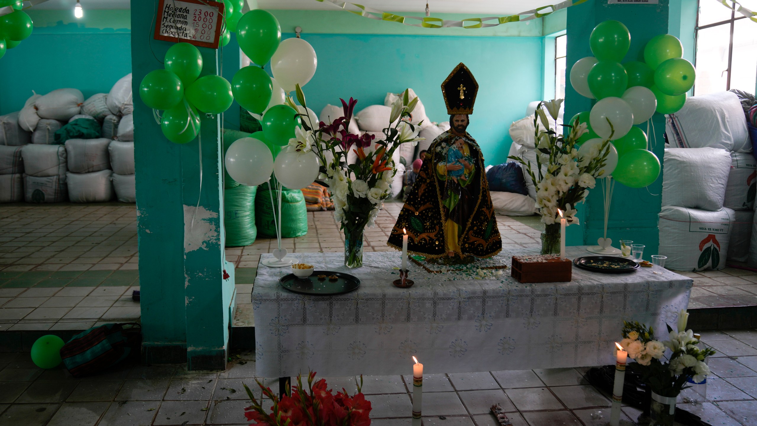 FILE - A statue of St. Joseph, flowers and balloons adorn an altar inside a legal coca leaf market marking the National Day of Chewing Coca Leaf, in La Paz, Bolivia, March 19, 2022. (AP Photo/Juan Karita, File)