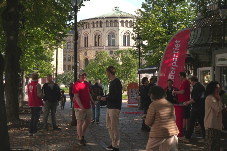 Campaign volunteers from the Labour Party, wearing red, engage with people near the Norwegian Parliament building in Oslo, Sunday, Sept. 7, 2025. (AP Photo/Kostya Manenkov)