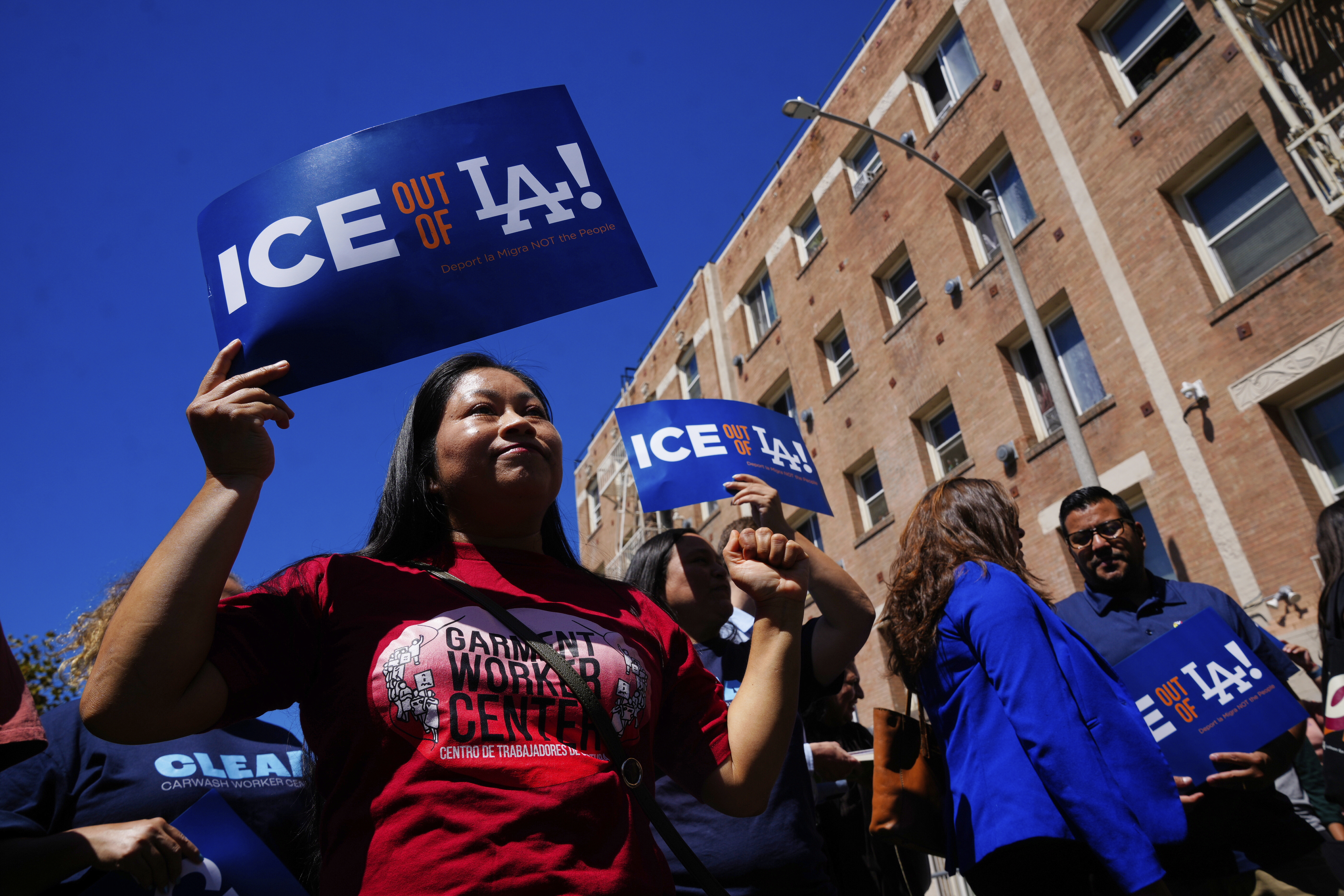 Gloria Miguel, left, with the Garment Worker Center holds a sign during a press conference in reaction to the Supreme Court's decision that clears the way for sweeping immigration operations in Los Angeles to continue on Monday, Sept. 8, 2025, in Los Angeles. (AP Photo/Damian Dovarganes)