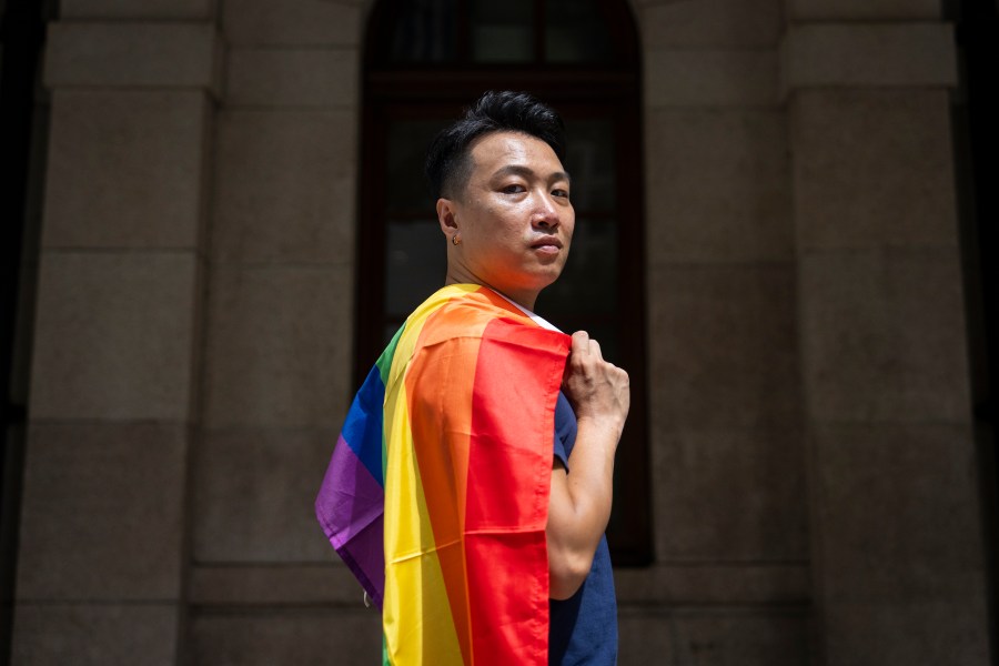 Jimmy Sham, gay rights activist and former pro-democracy district councillor, holds rainbow flag as he poses for photographs in front of the court of final appeal in Hong Kong, Sunday, Aug. 24, 2025. (AP Photo/Chan Long Hei)