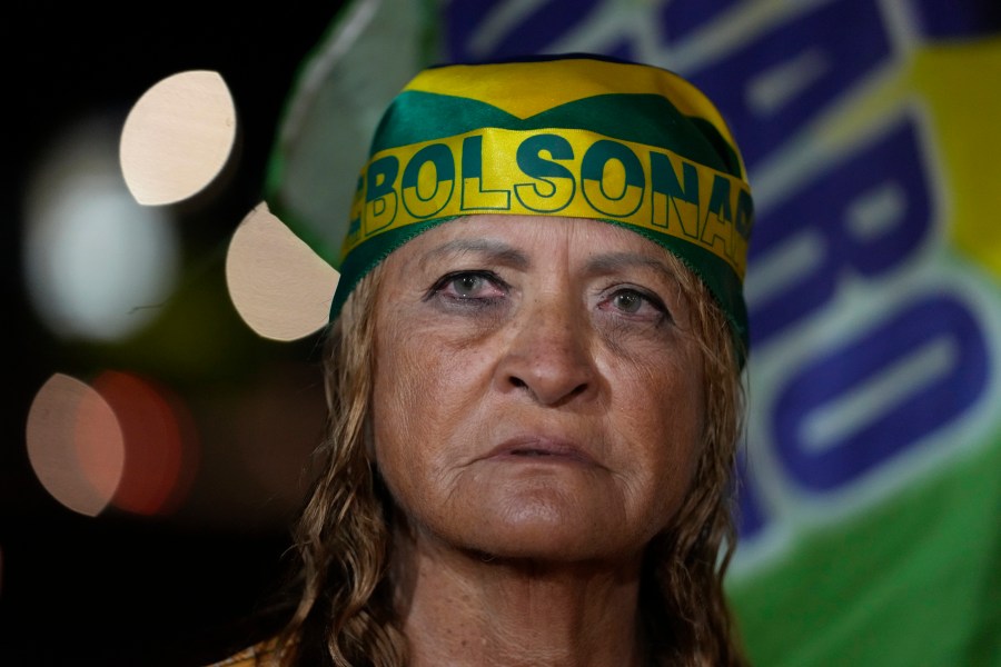 A supporter of former President Jair Bolsonaro prays during a vigil in his support near his home where he is under house arrest, in Brasília, Brazil, Tuesday, Sept. 9, 2025. (AP Photo/Eraldo Peres)