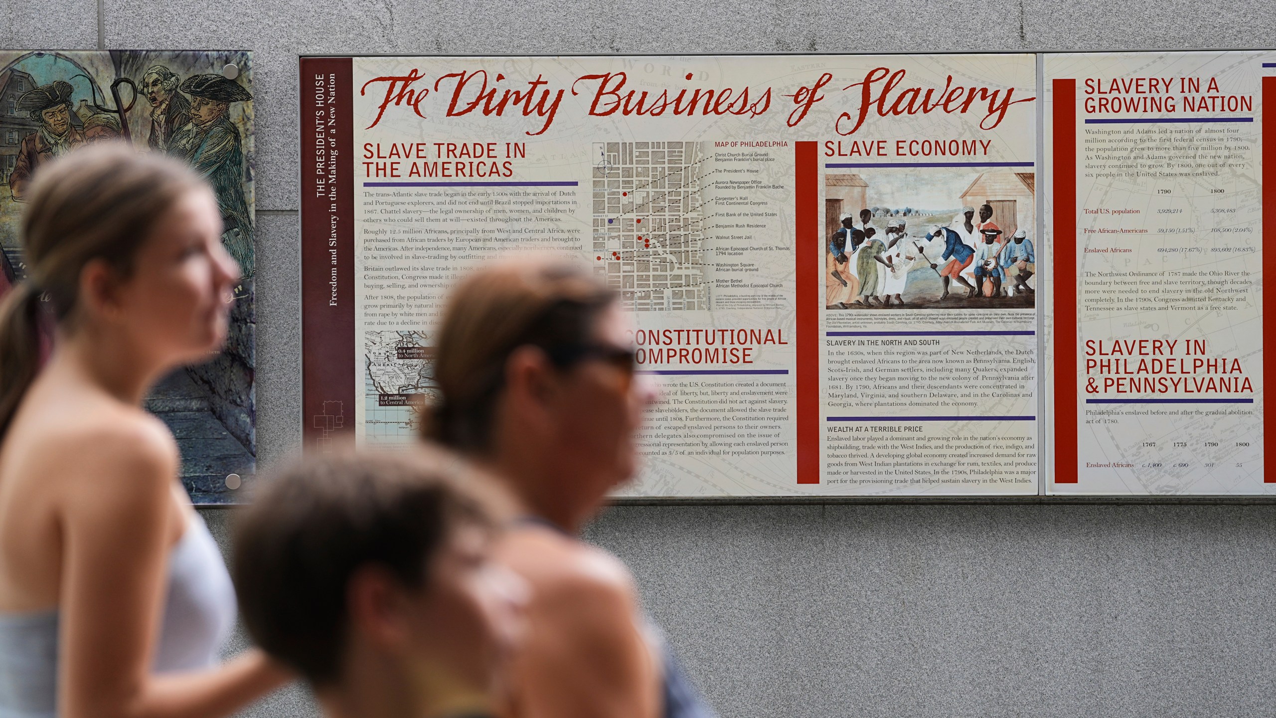 People walk past an informational panel at President's House Site Tuesday, Aug. 19, 2025, in Philadelphia. (AP Photo/Matt Rourke)