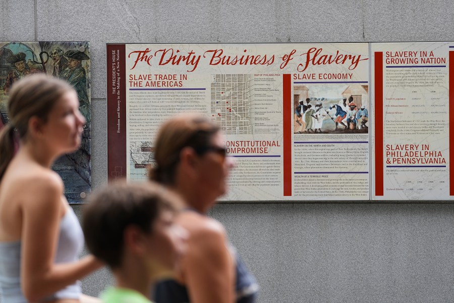 People walk past an informational panel at President's House Site Tuesday, Aug. 19, 2025, in Philadelphia. (AP Photo/Matt Rourke)