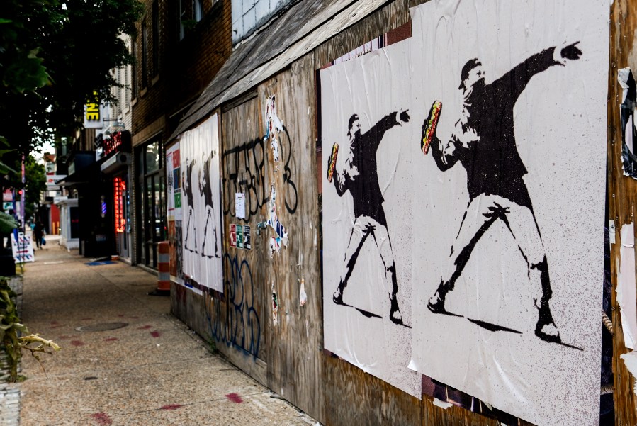 Posters of a person throwing a sandwich are pictured along H Street, Sunday, Aug. 17, 2025, in Washington. (AP Photo/Julia Demaree Nikhinson)
