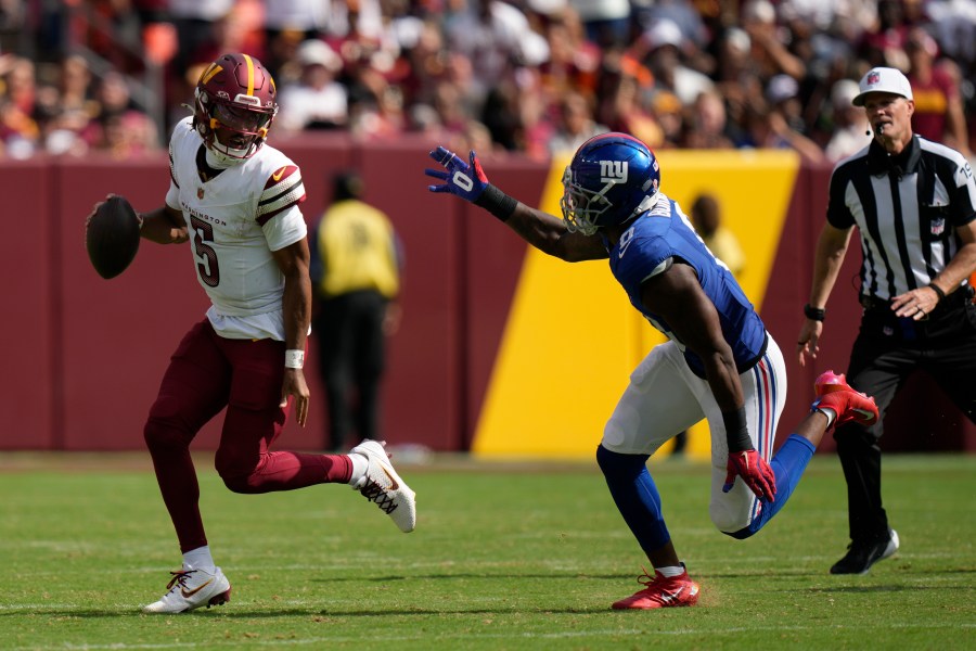 Washington Commanders quarterback Jayden Daniels (5) is chased by New York Giants linebacker Brian Burns (0) during the second half of an NFL football game, Sunday, Sept. 7, 2025, in Landover, Md. (AP Photo/Stephanie Scarbrough)
