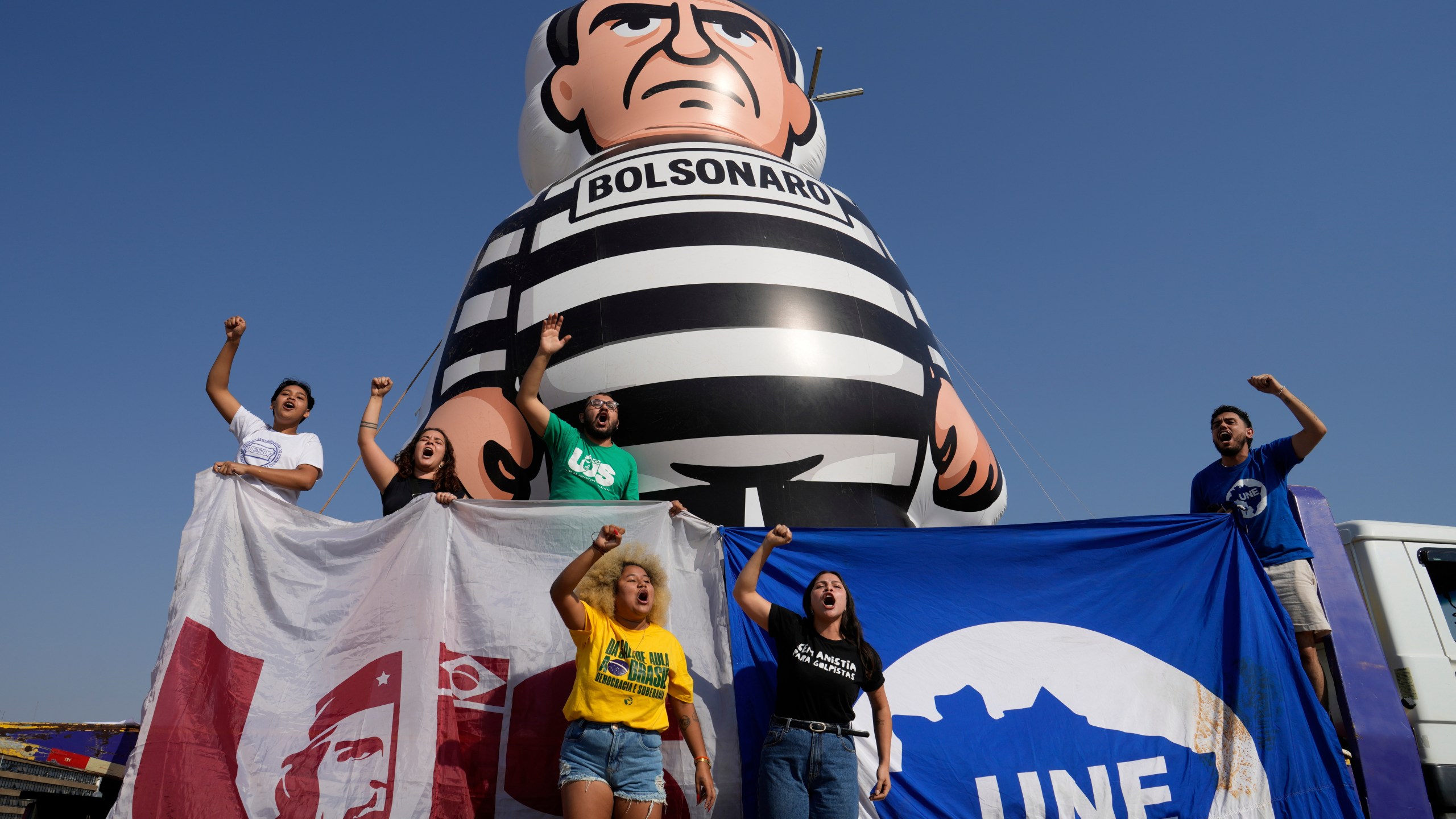 University students display an inflatable doll of Brazil's former President Jair Bolsonaro wearing prisoner garb in Brasilia, Brazil, Friday, Sept. 12, 2025, the morning after the Supreme Court convicted and sentenced him to prison for attempting a coup to remain in office despite his 2022 electoral defeat. (AP Photo/Eraldo Peres)