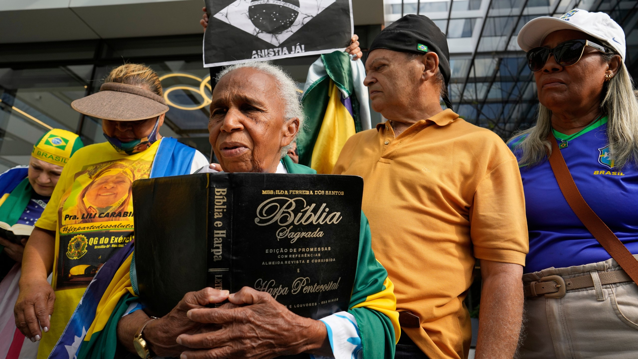 A supporter holding a Bible waits for the arrival of former President Jair Bolsonaro at a hospital, after he was temporarily allowed out of house arrest for medical treatment, in Brasilia, Brazil, Sunday, Sep. 14, 2025. (AP Photo/Eraldo Peres)