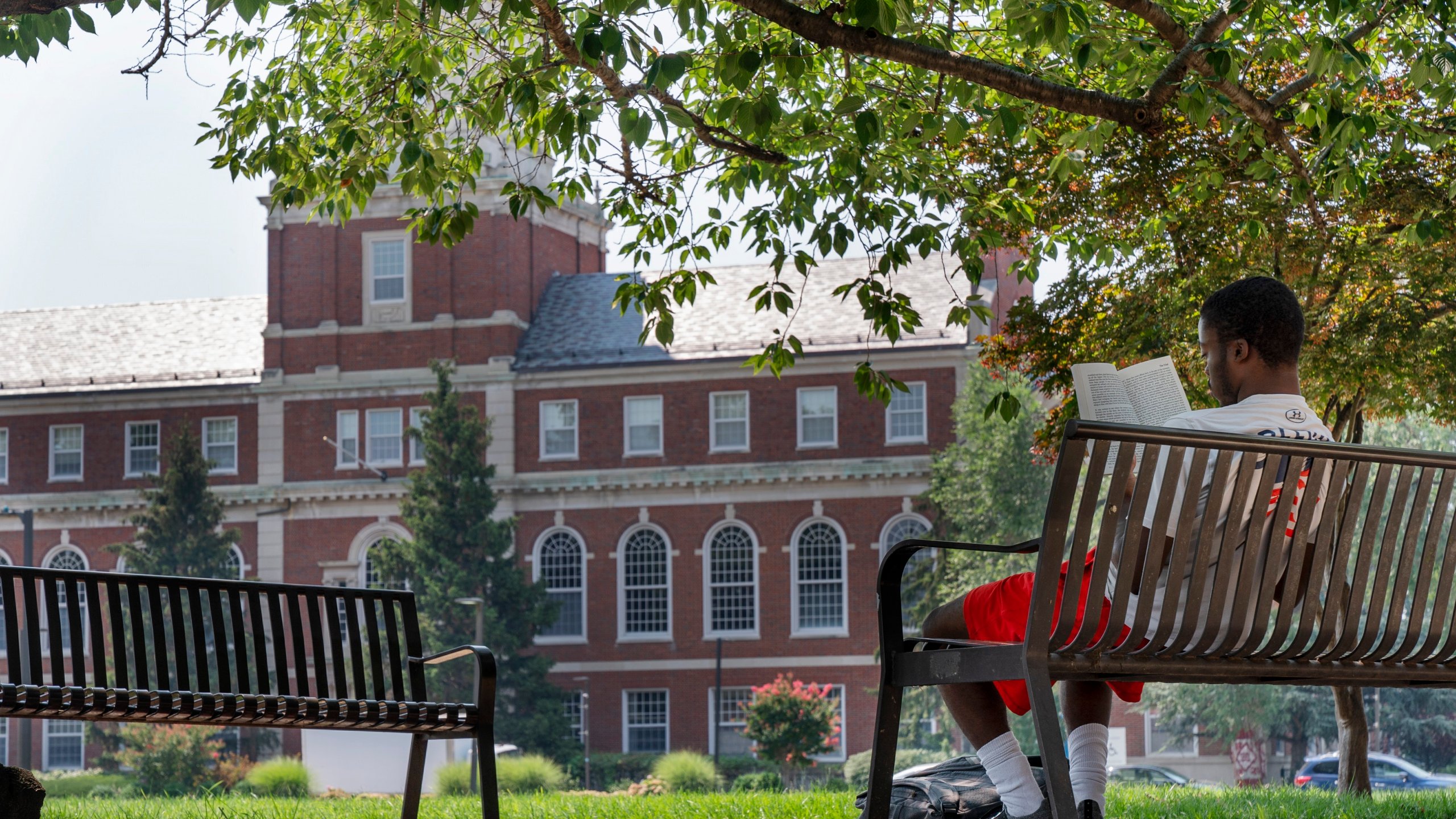 FILE - With the Founders Library in the background, a young man reads on Howard University campus July 6, 2021, in Washington. (AP Photo/Jacquelyn Martin, File)