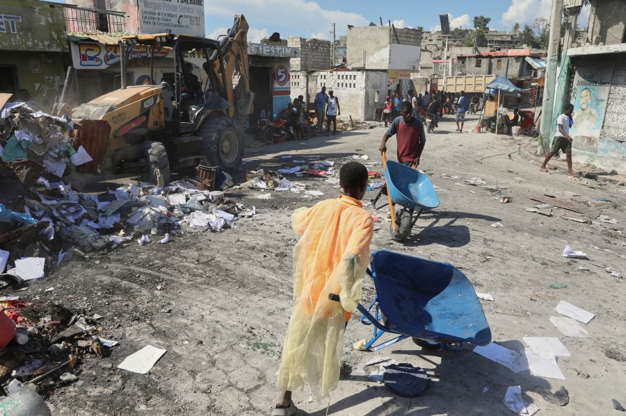 Youths use wheelbarrows to carry debris out of their homes, which were damaged by gang violence, in the Solino neighborhood of Port-au-Prince, Haiti, Wednesday, Sept. 10, 2025. (AP Photo/Odelyn Joseph)