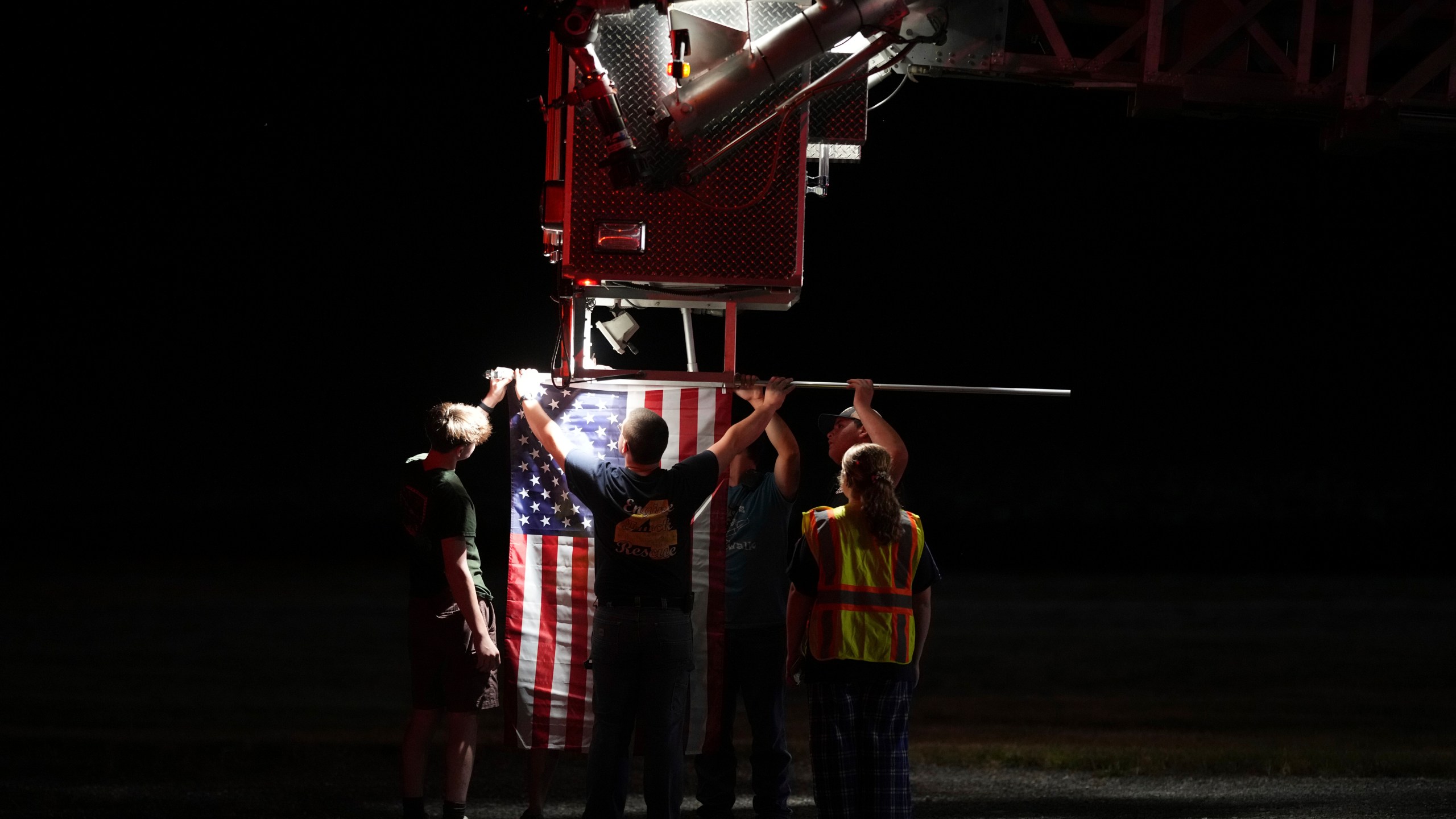 Firefighters attach an American flag to a firetruck before a procession after multiple police officers were shot and killed Wednesday, Sept. 17, 2025, in Spring Grove, Pa. (AP Photo/Matt Slocum)