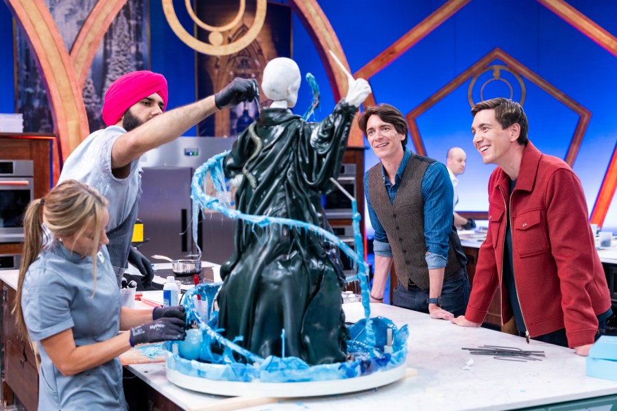 This image released by Food Network shows hosts Oliver Phelps, right, and James Phelps, watching contestants Katie Bonzer, left, and Jujhar Mann on the set of the competition series "Harry Potter: Wizards of Baking." (Anders Krusberg/Food Network via AP)