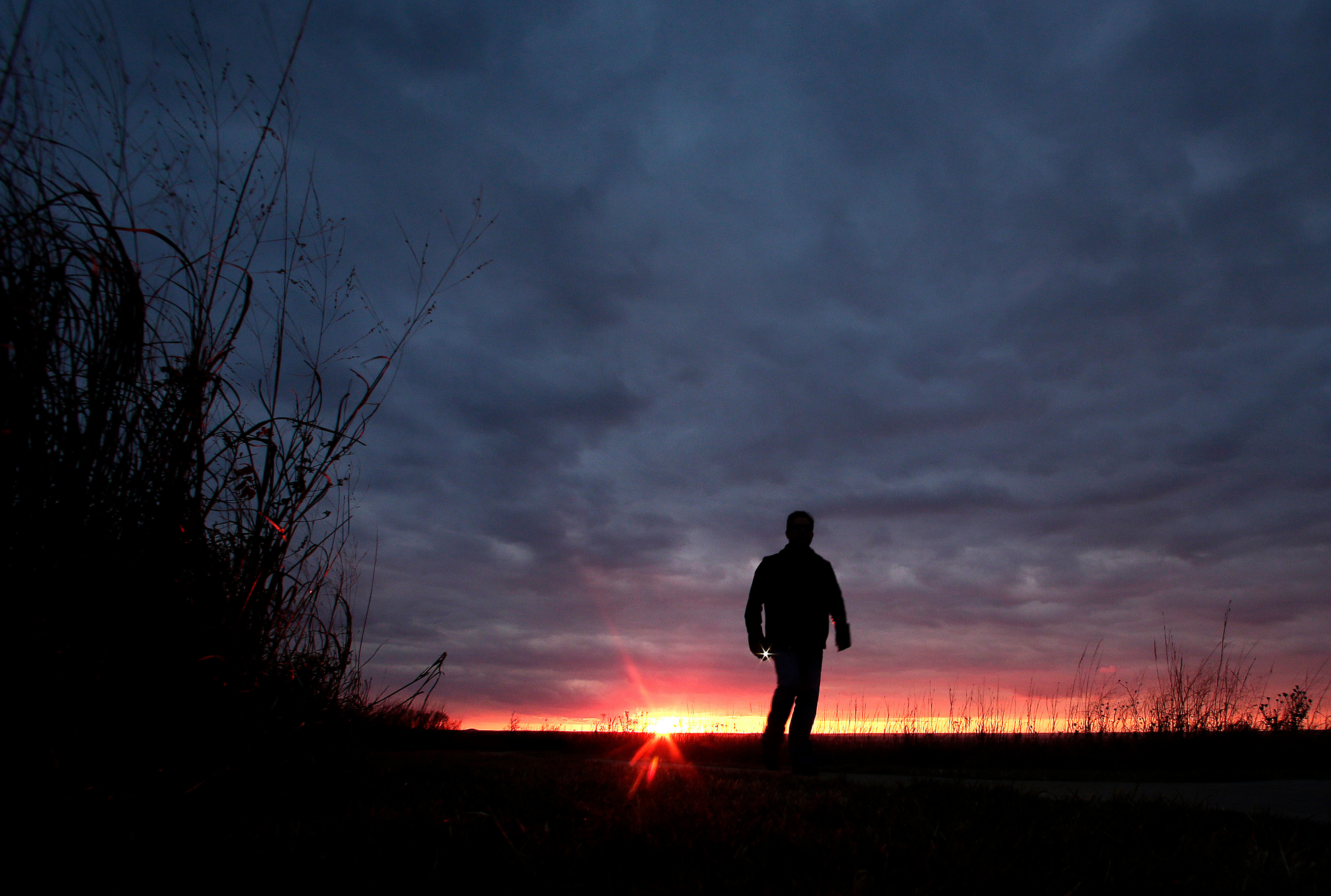 FILE - A man walks along a trail during sunset near Manhattan, Kan., on Nov. 20, 2015. (AP Photo/Charlie Riedel, File)