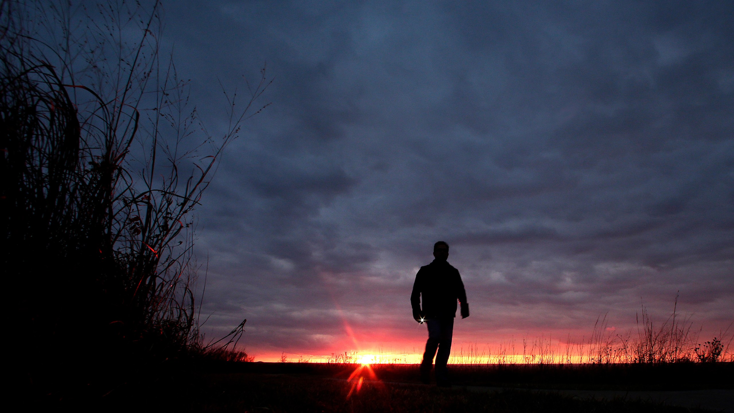FILE - A man walks along a trail during sunset near Manhattan, Kan., on Nov. 20, 2015. (AP Photo/Charlie Riedel, File)
