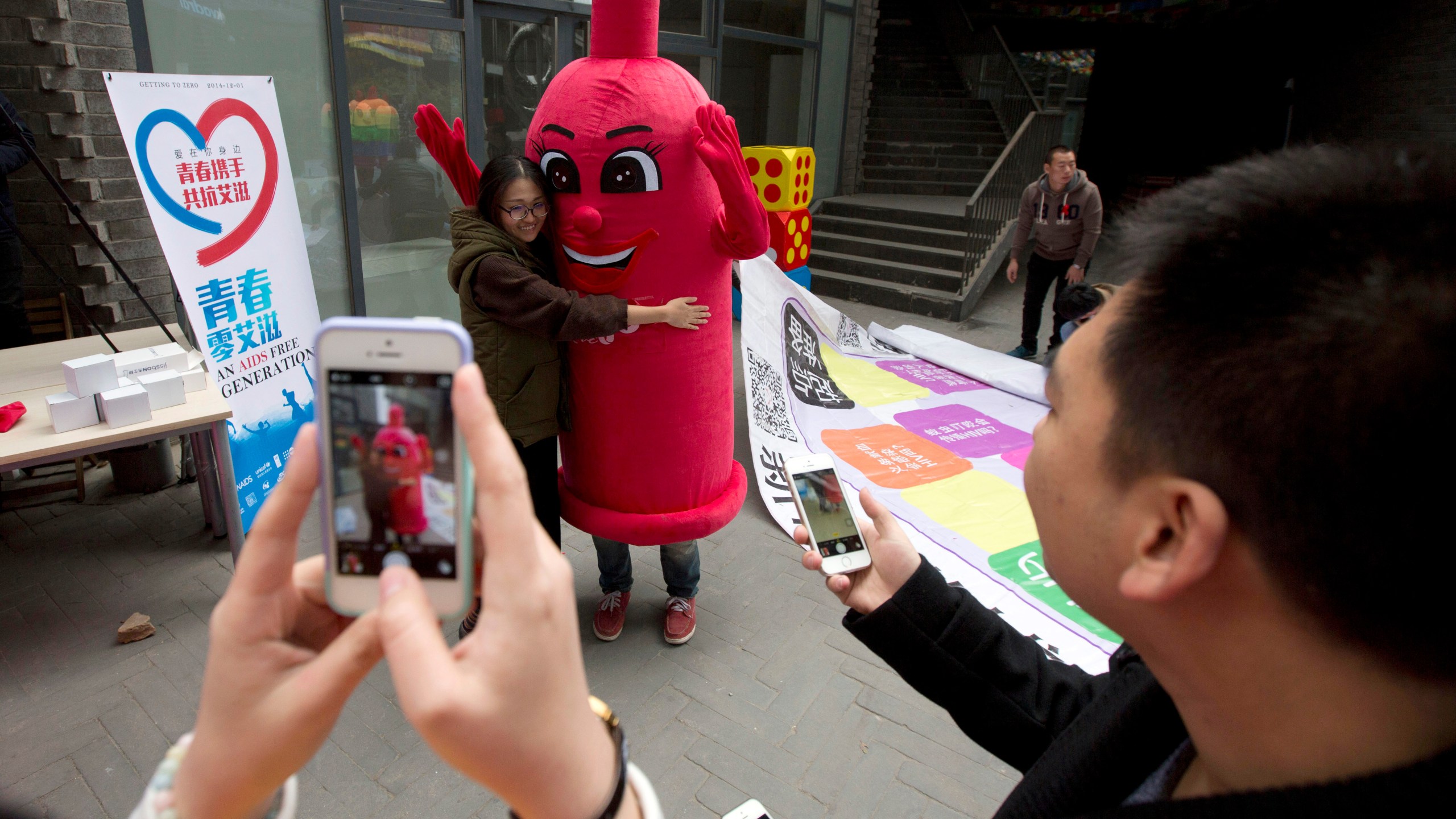 FILE - A participant hugs a condom mascot during an event to promote awareness of HIV testing ahead of the Dec 1 World AIDS Day, in Beijing, China, Thursday, Nov. 27, 2014. (AP Photo/Ng Han Guan, File)