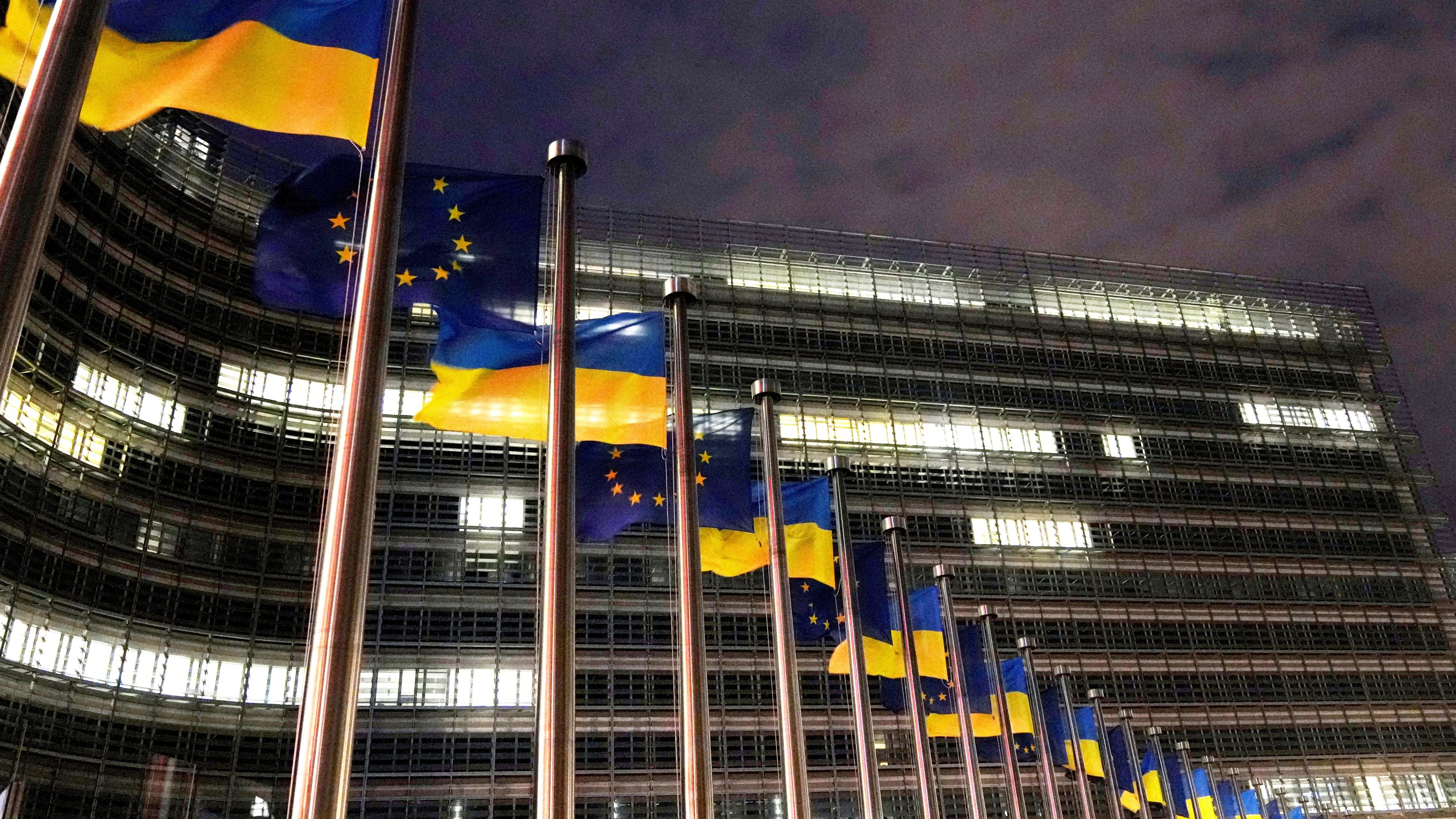 FILE - The European Union and Ukrainian flags flap in the wind to mark the third anniversary of Russia's full-scale invasion of Ukraine outside EU headquarters in Brussels, Feb. 24, 2025. (AP Photo/Virginia Mayo, File)