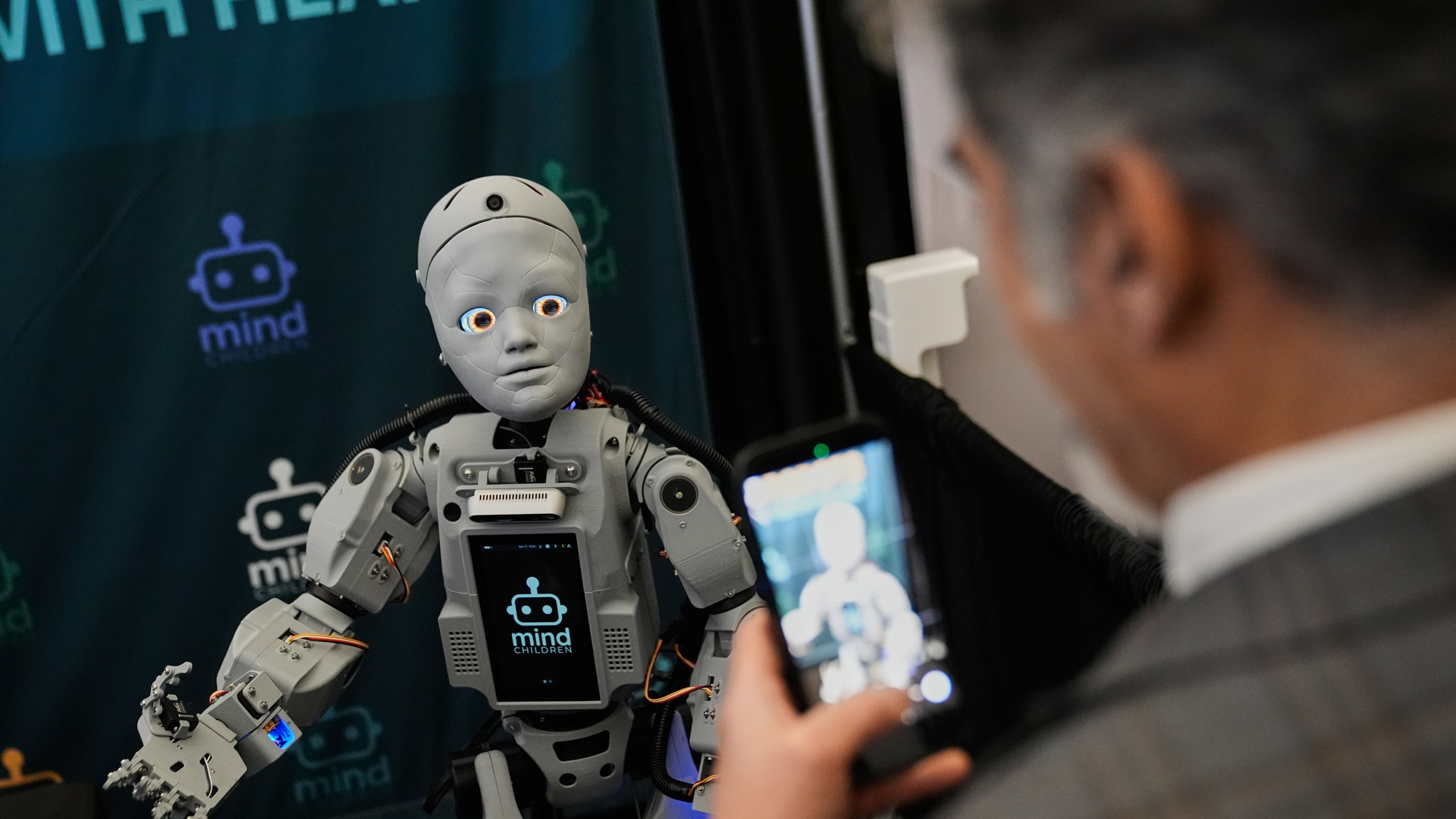 A man records a humanoid robot inside the exhibition room at the Humanoids Summit, Thursday, Dec. 11, 2025, in Mountain View, Calif. (AP Photo/Godofredo A. Vásquez)