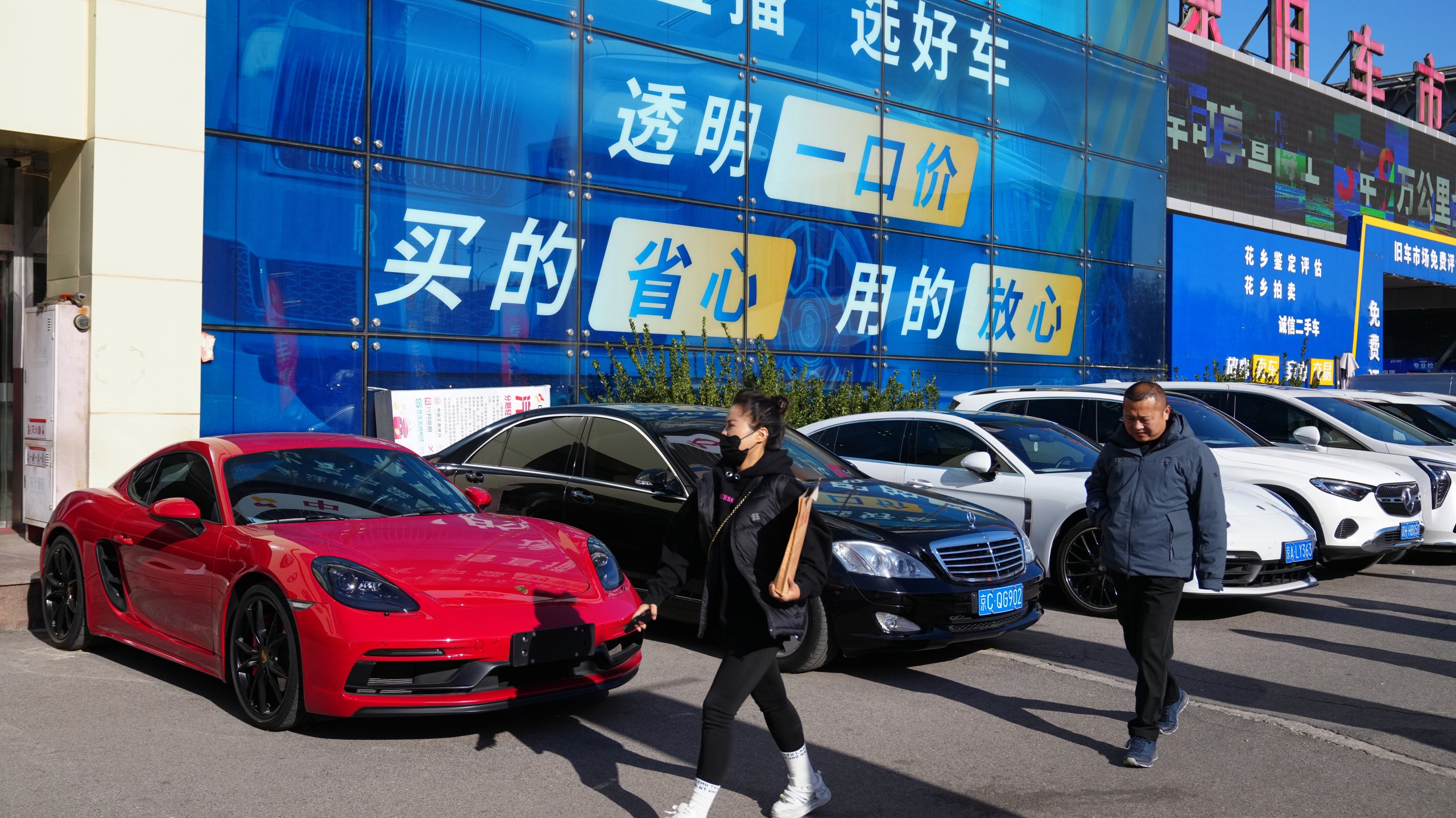 People walk past a second hand market for luxury cars in Beijing, Tuesday, Nov. 25, 2025. (AP Photo/Andy Wong)