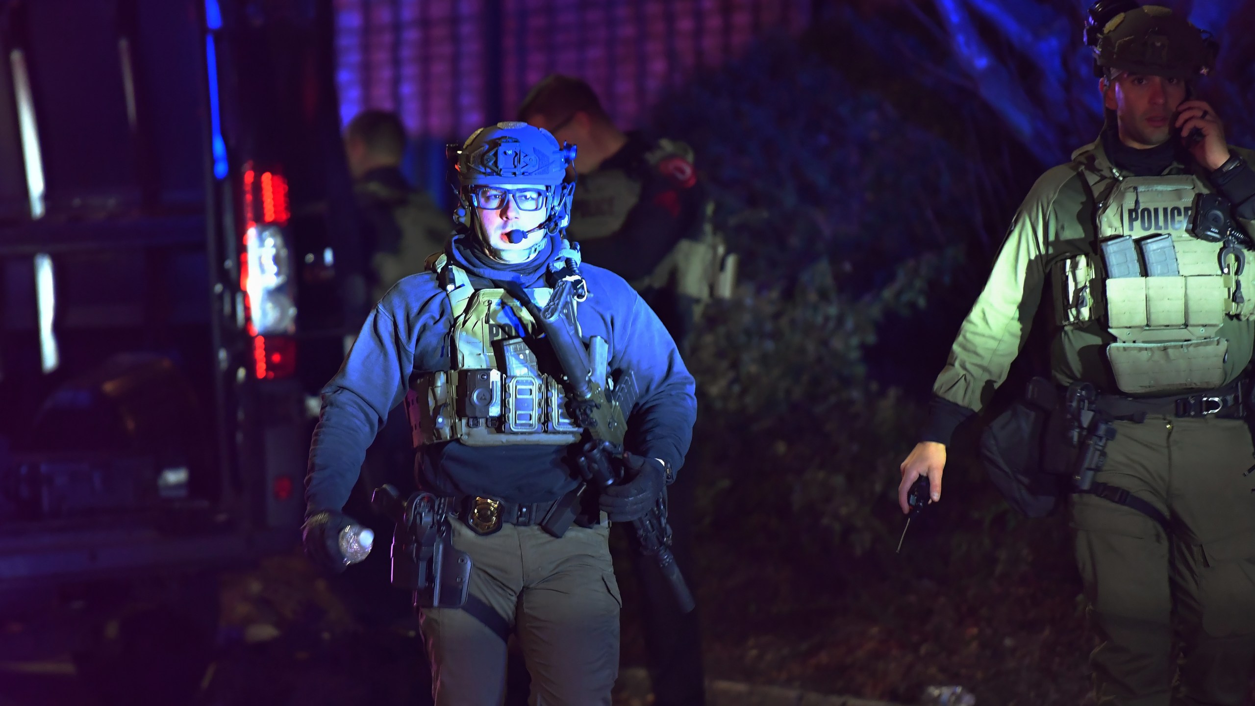 A law enforcement official carries a rifle in a neighborhood near Brown University, Saturday, Dec. 13, 2025, in Providence, R.I. during the investigation of a shooting. (AP Photo/Steven Senne)